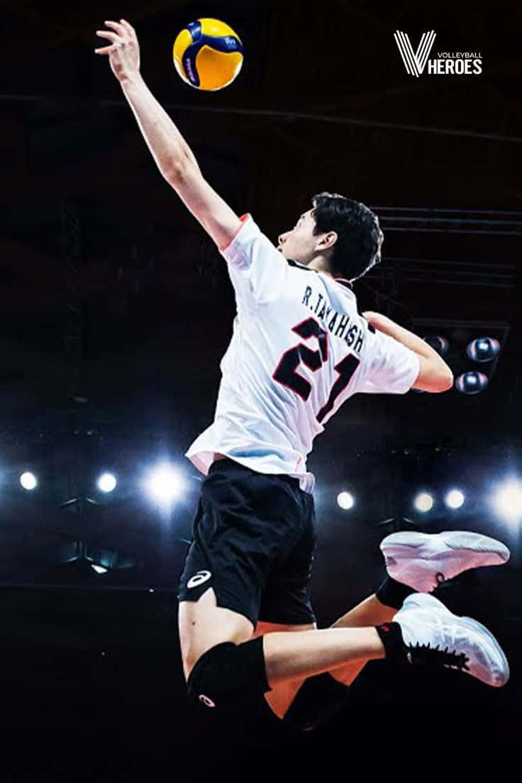 排球運動員在半空中於黑暗場館中在聚光燈下扣球。