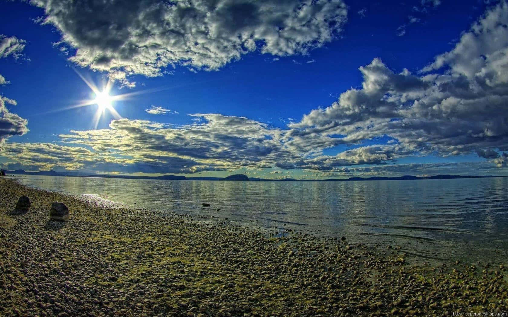陽光穿過雲層照耀在平靜的海面和卵石灘上