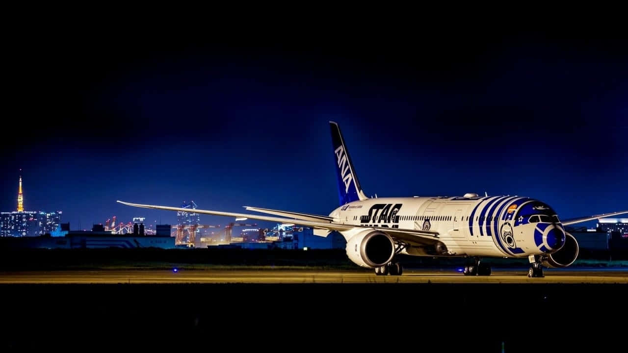 ANA星戰R2-D2飛機夜晚在跑道上，東京城市燈光。