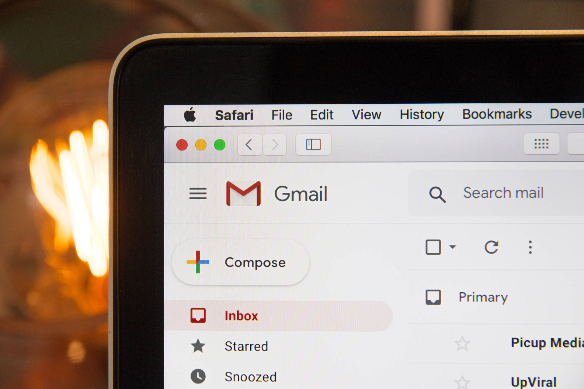 手提電腦屏幕顯示 Gmail 應用程式，背景有一個發光燈泡。