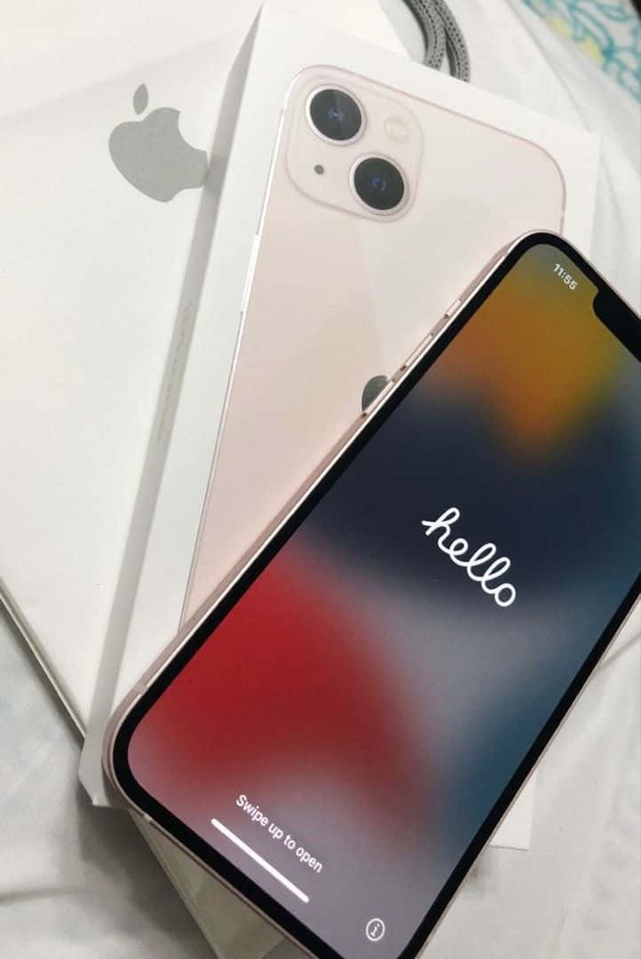 最新最強 — 介紹全新 iPhone 12 壁紙 — 玫瑰金 iPhone 11 放在白色盒子上，置於床單上，屏幕顯示 'hello'，背景為彩色漸變。