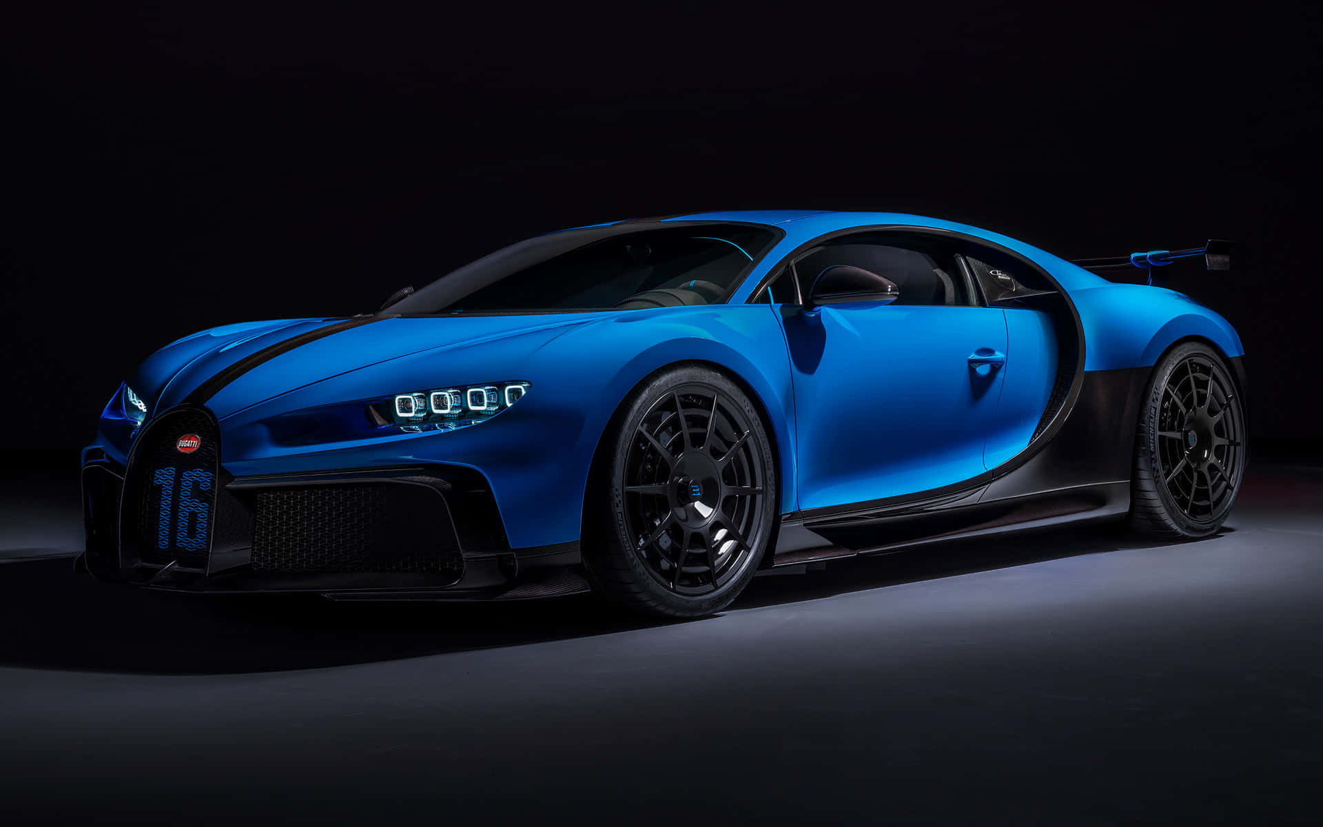 藍色Bugatti Chiron Super Sport 300+在黑暗的攝影棚地板上，帶有戲劇性的燈光。