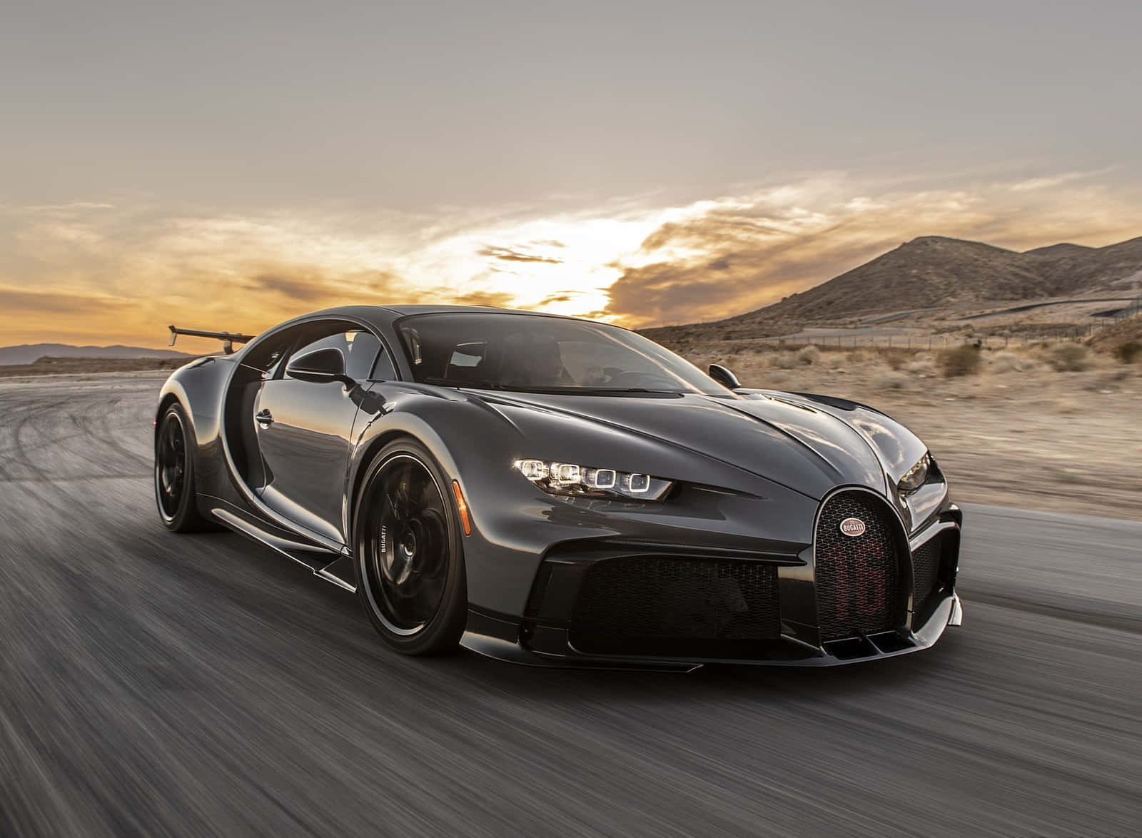 灰色Bugatti Chiron在金色日落下的沙漠公路上疾馳。