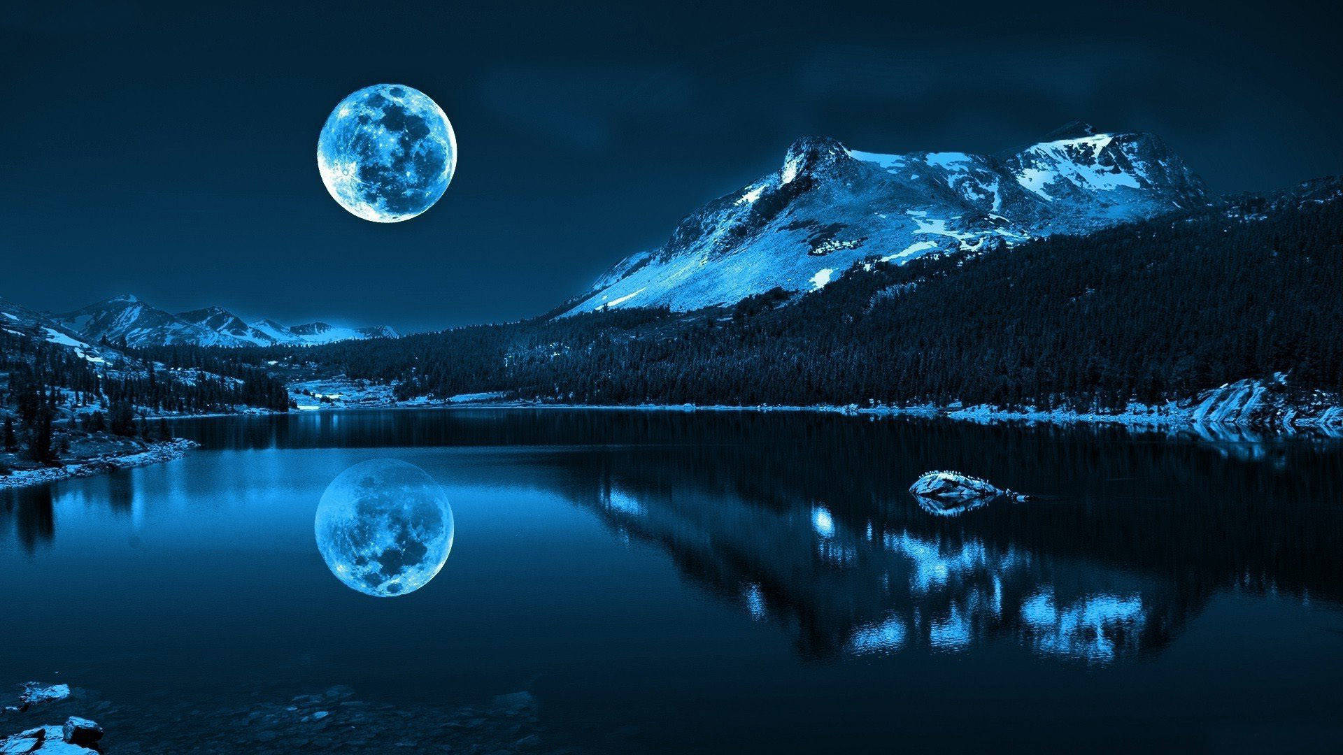 月光下的山間冬夜 壁紙 — 一輪滿月在白雪覆蓋的山峰上閃耀，倒映在黑暗夜空下寧靜的藍色湖泊中。