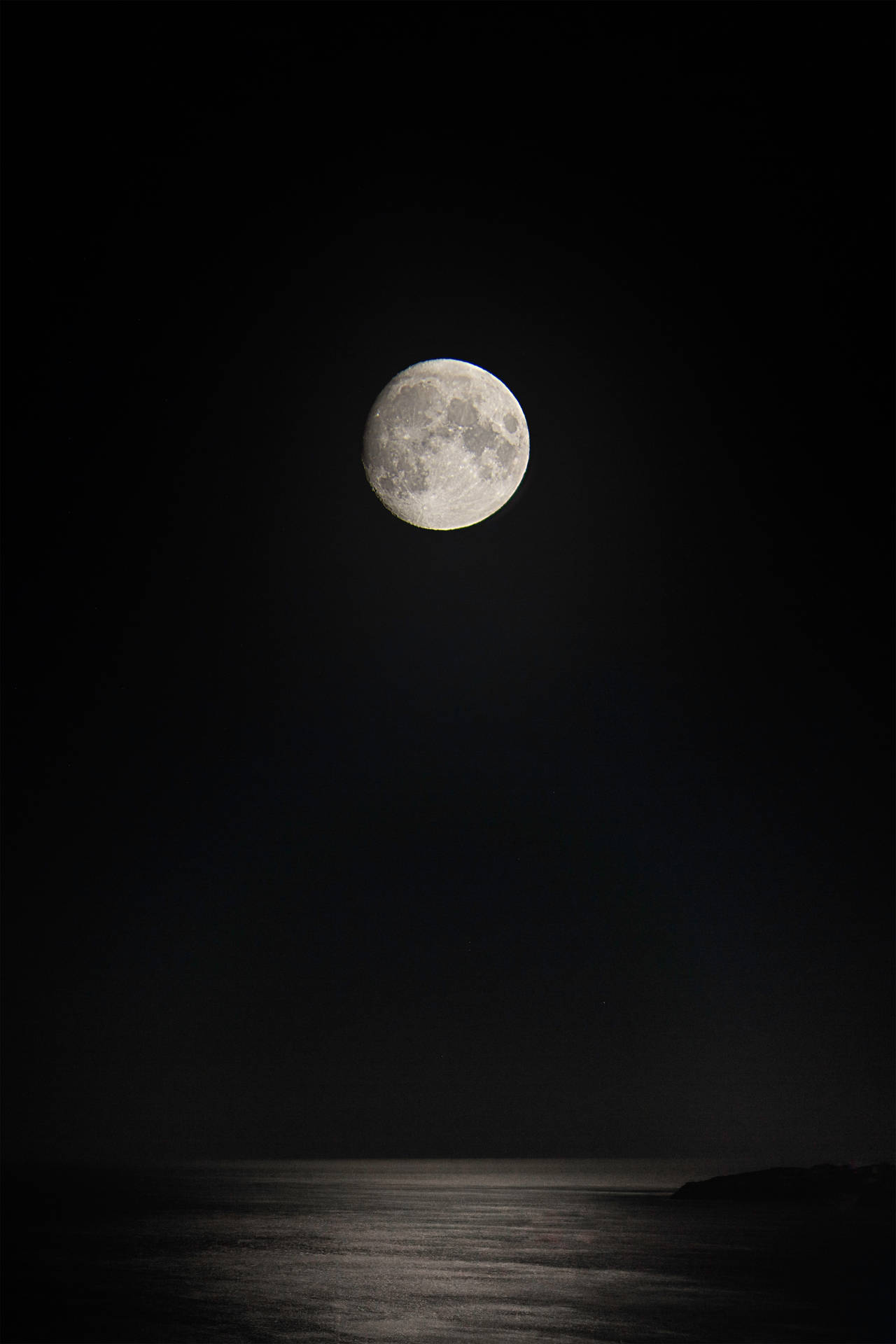 滿月映照在平靜的海洋上，夜空黑暗