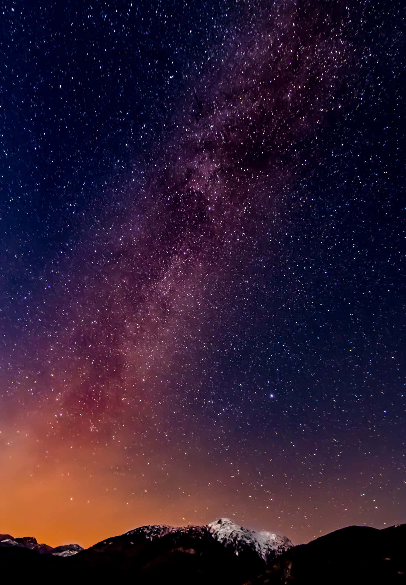 在充滿活力的星空下，積雪的山峰與銀河。