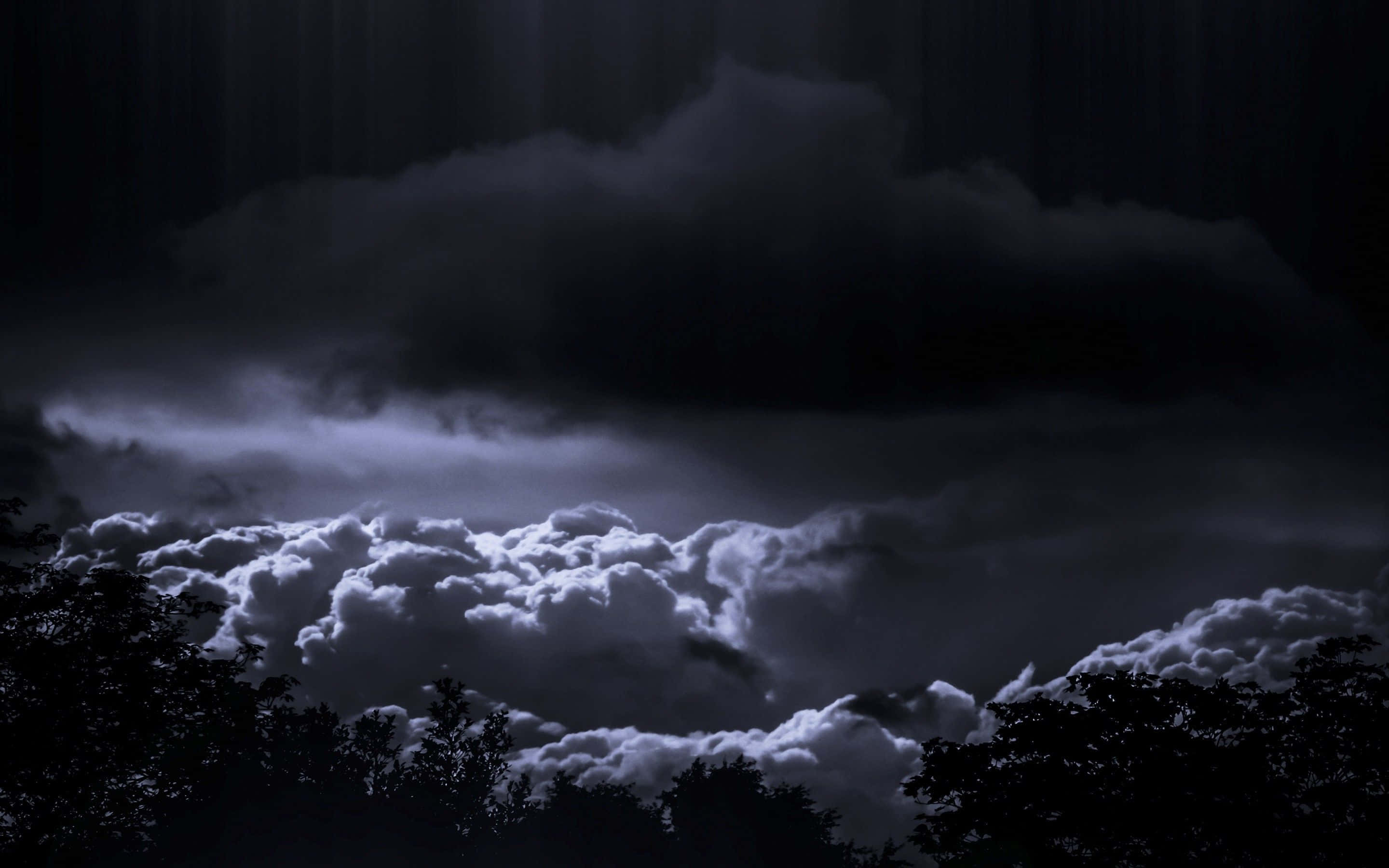 Dark Storm 桌布 壁紙 — 月光照亮嘅戲劇性風暴雲層懸浮喺剪影樹梢之上，營造出憂鬱嘅夜空。