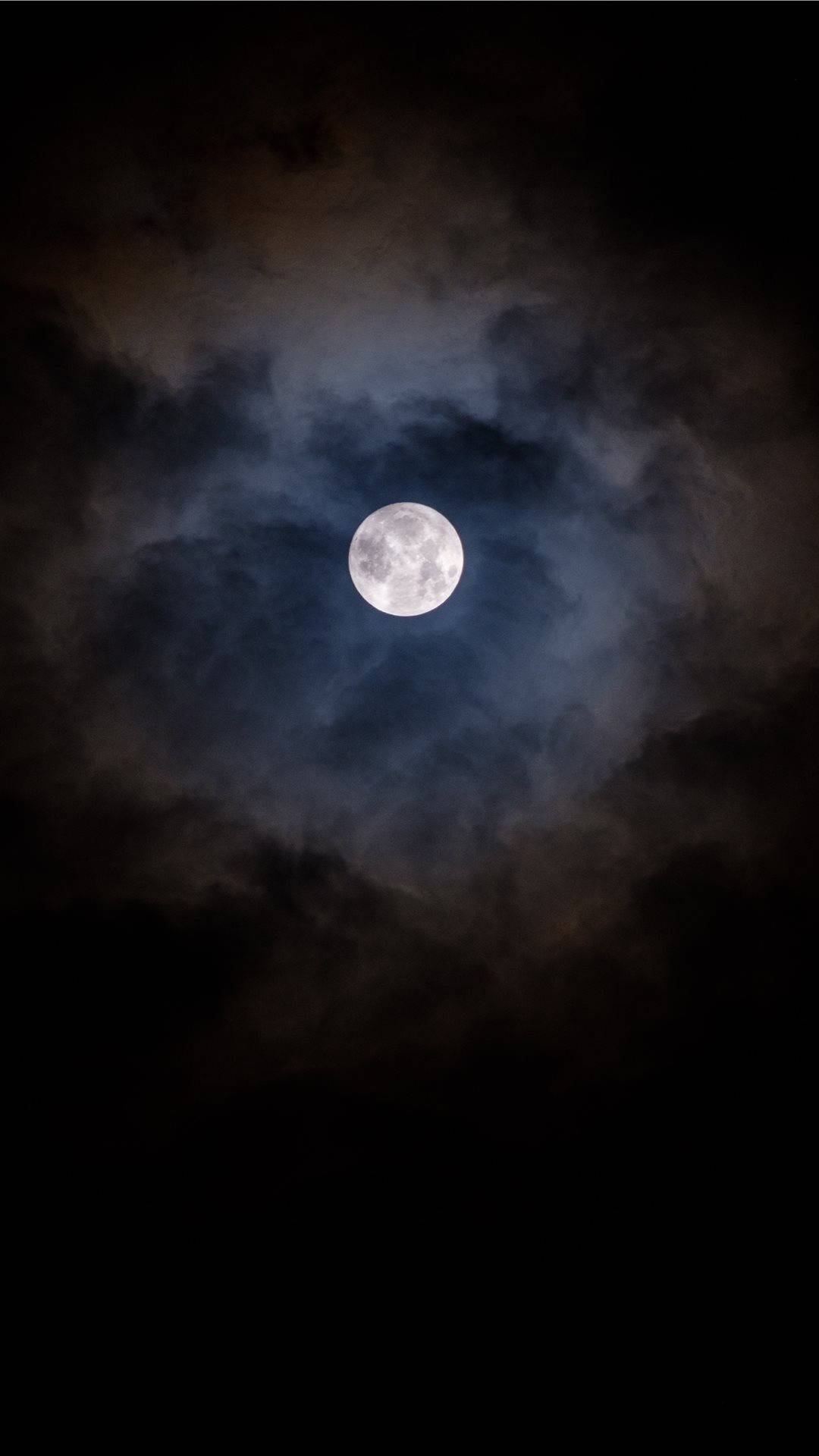 滿月在夜間穿過黑暗的暴風雲閃耀。