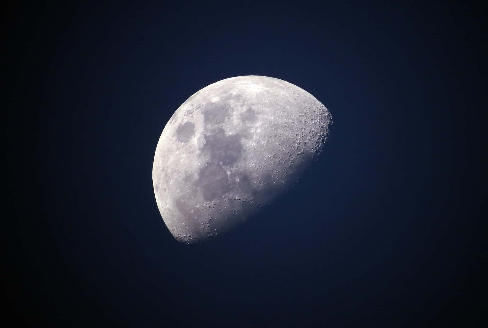 一個彎月，在黑暗的夜空中可見隕石坑。