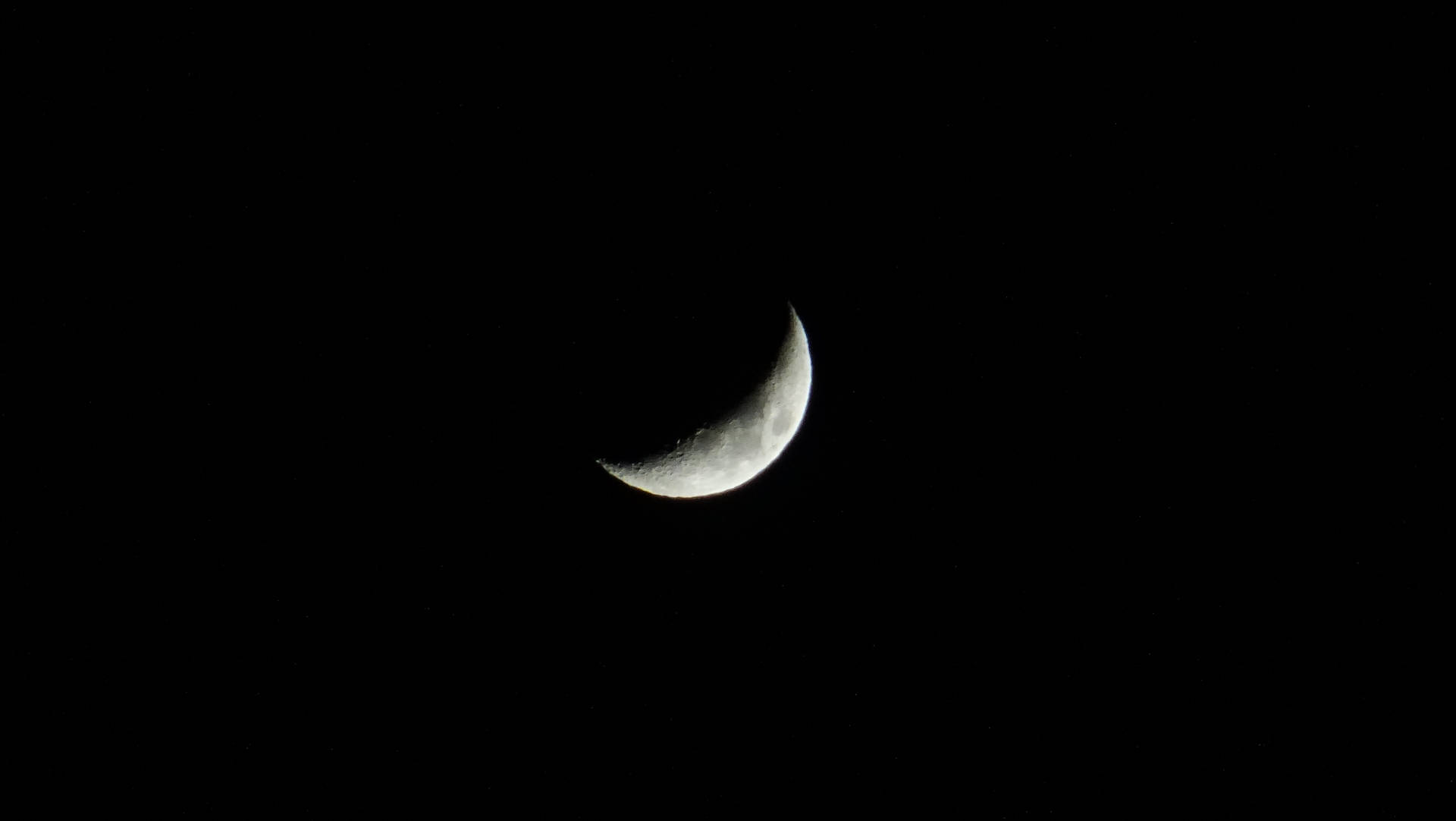 月球 壁紙 — 一彎精緻的月牙在漆黑的夜空中柔和發光，看不見任何星星。