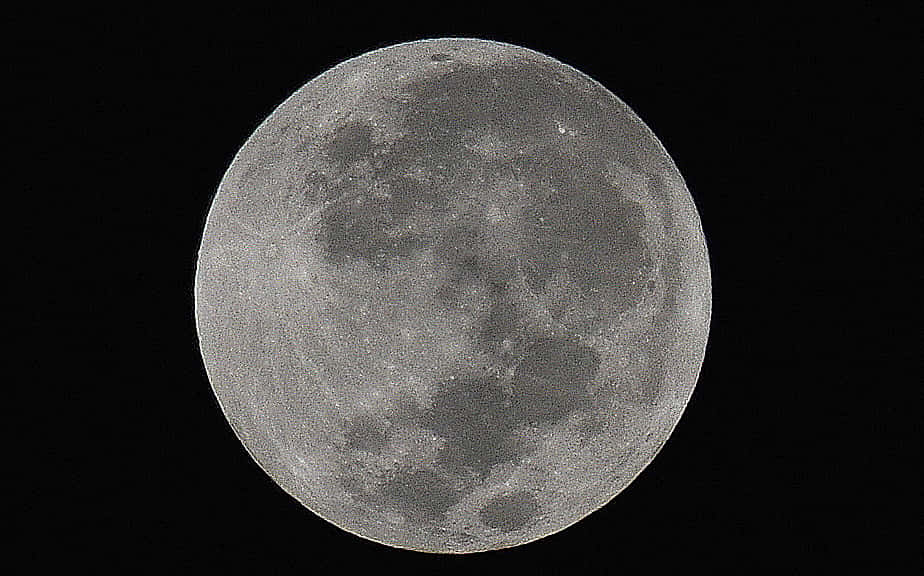 Perigee 桌布 壁紙 — 月球佈滿隕石坑的表面在漆黑天空中柔和發光的詳細特寫。