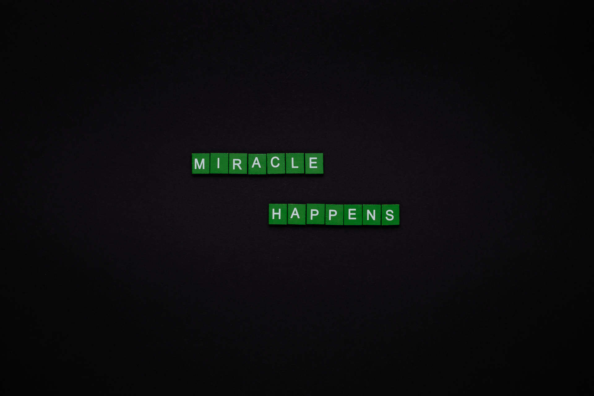 綠色單詞瓷磚在深色背景上拼出 miracle happens。