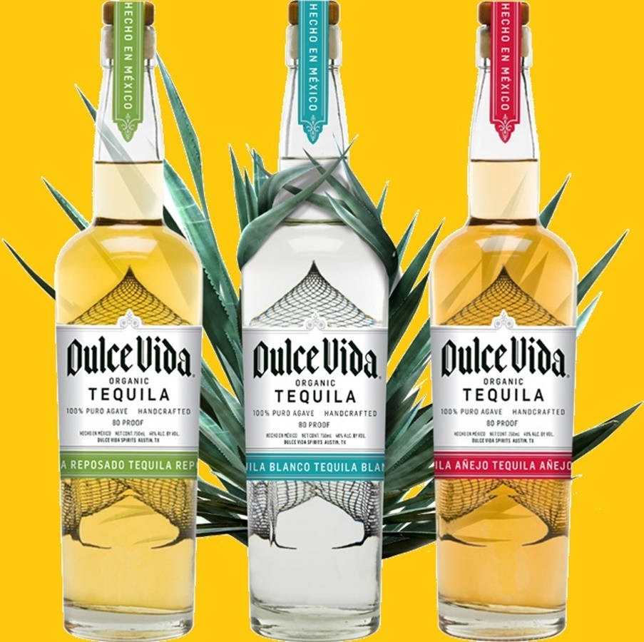 三瓶Dulce Vida龍舌蘭酒與龍舌蘭葉在黃色背景上。