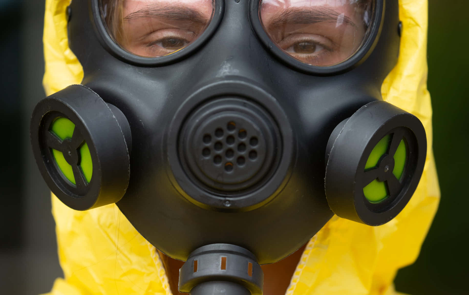 穿著黃色防護服的人戴著黑色防毒面具和綠色濾鏡。