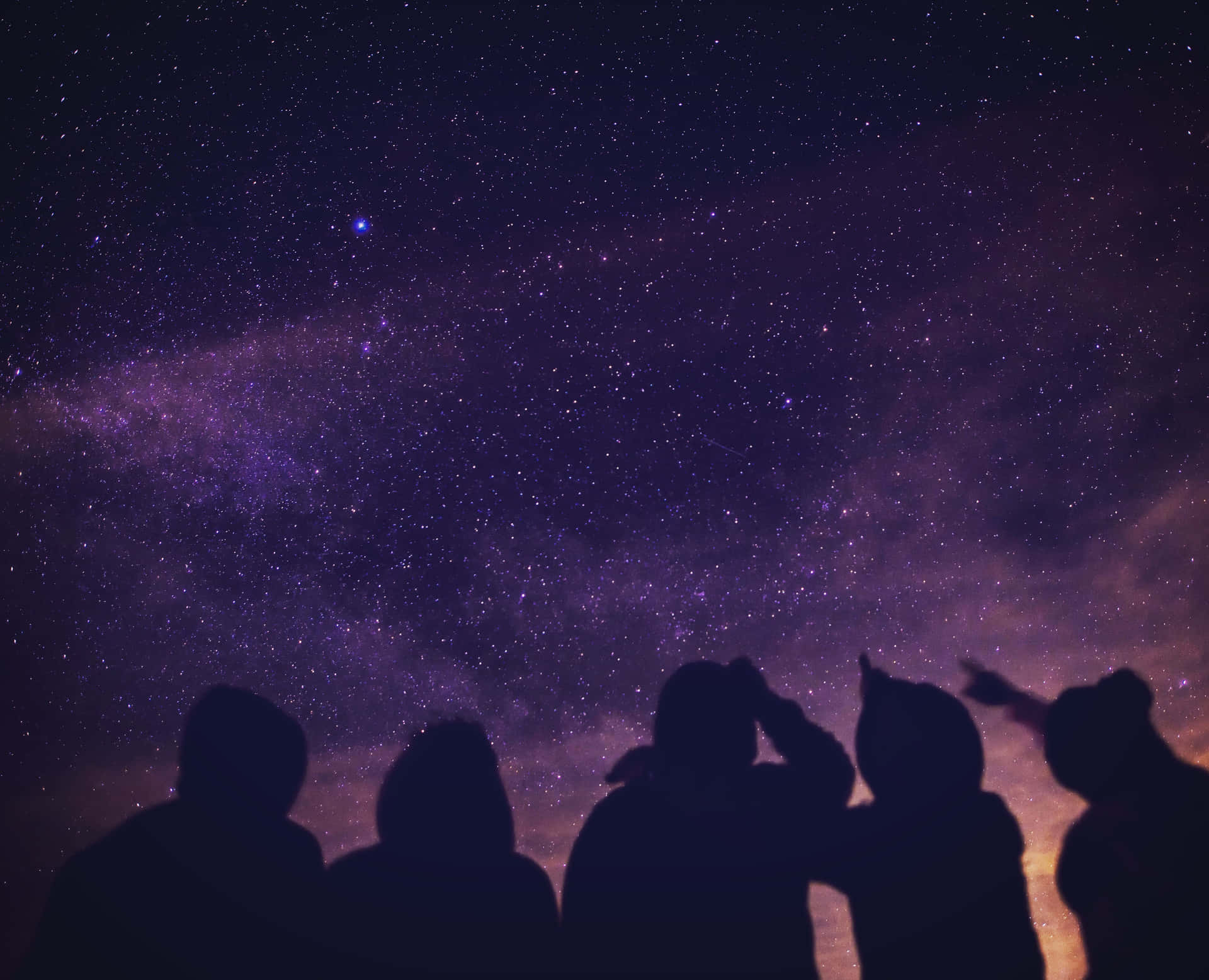 一群人剪影在星空下觀看銀河系。