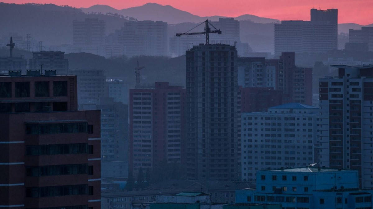 朝鮮平壤迷人夜景天際線 壁紙 — 黃昏時分朦朧的城市天際線，高聳的建築物和建築起重機在粉紅色和紫色的天空襯托下形成剪影。