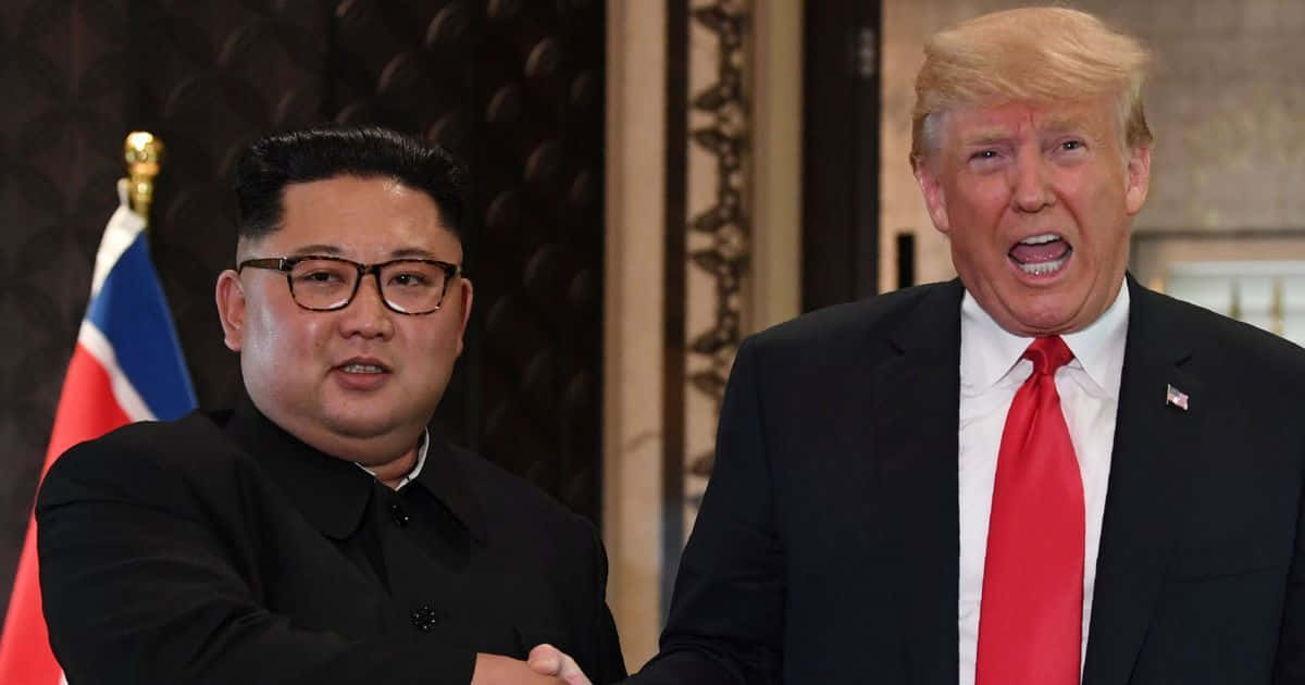 朝鮮獨裁者金正恩在軍事閱兵式上 壁紙 — 金正恩和唐納德·特朗普在一個正式的室內環境中握手，背後可見旗幟。