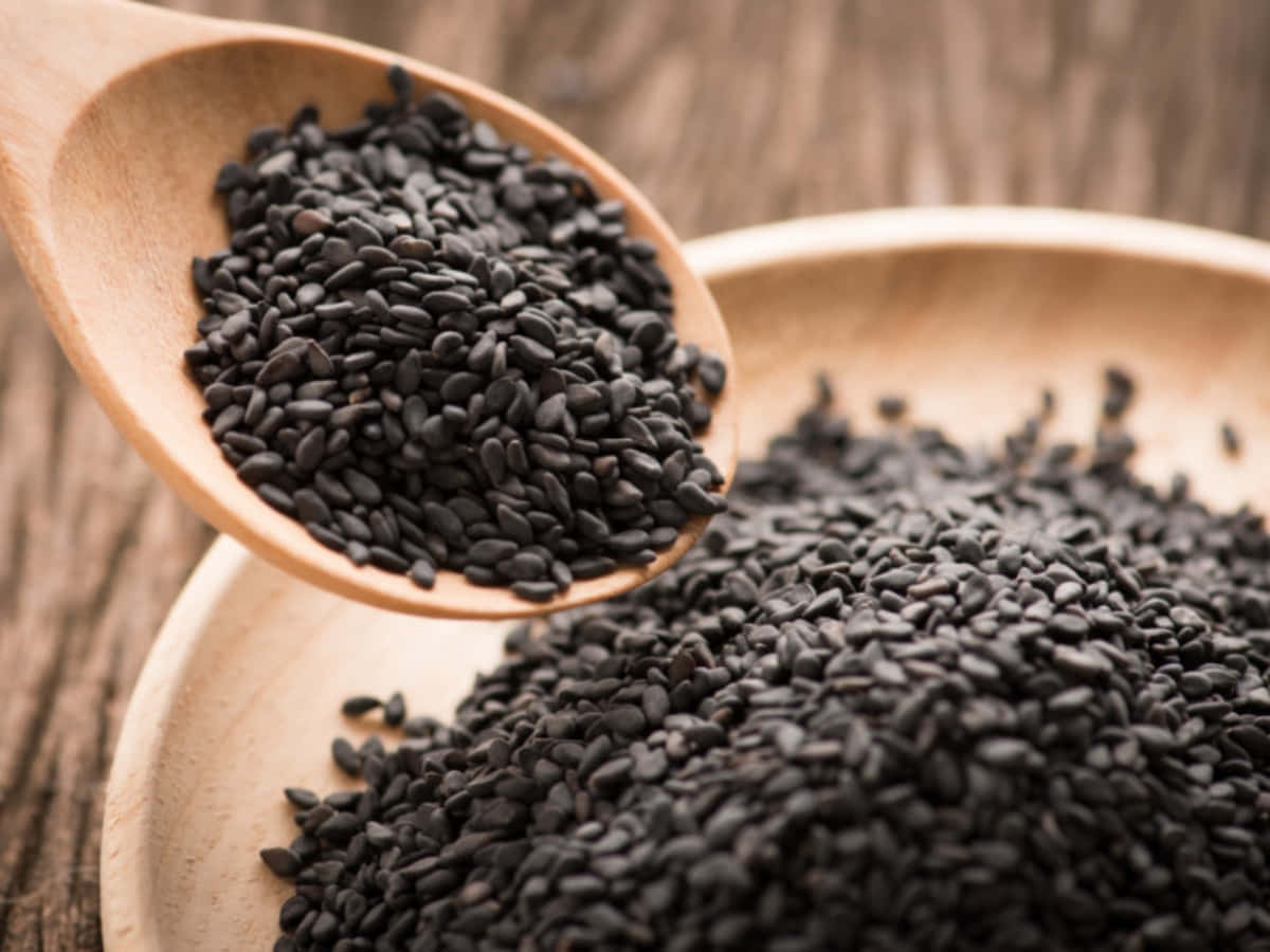 Black Sesame 桌布 壁紙 — 木勺將閃亮的黑芝麻舀起，置於相配的木碗之上，下方是質樸的木質表面。