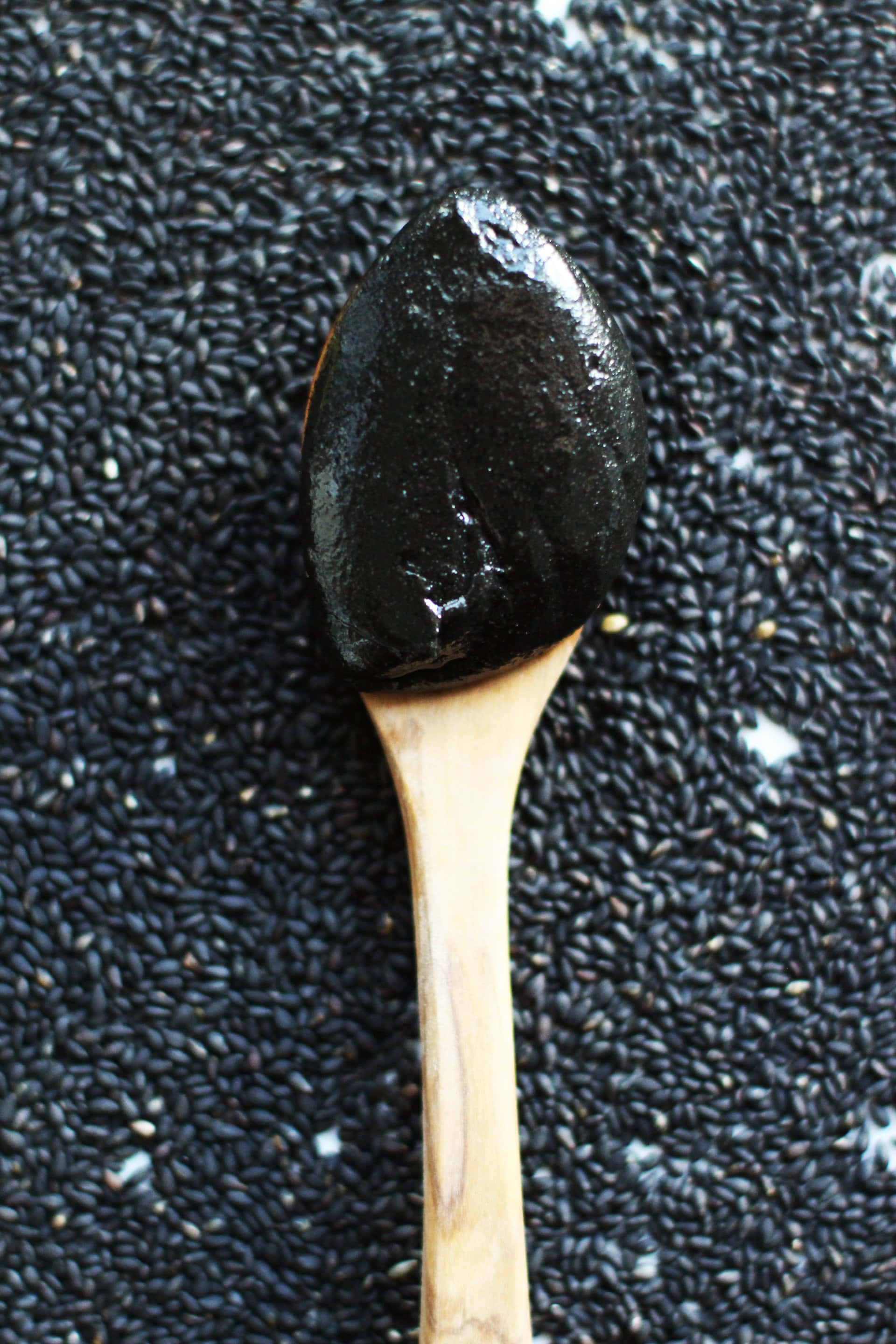 Black Sesame 桌布 壁紙 — 木匙盛著亮澤的黑芝麻醬，置於深色芝麻粒上。