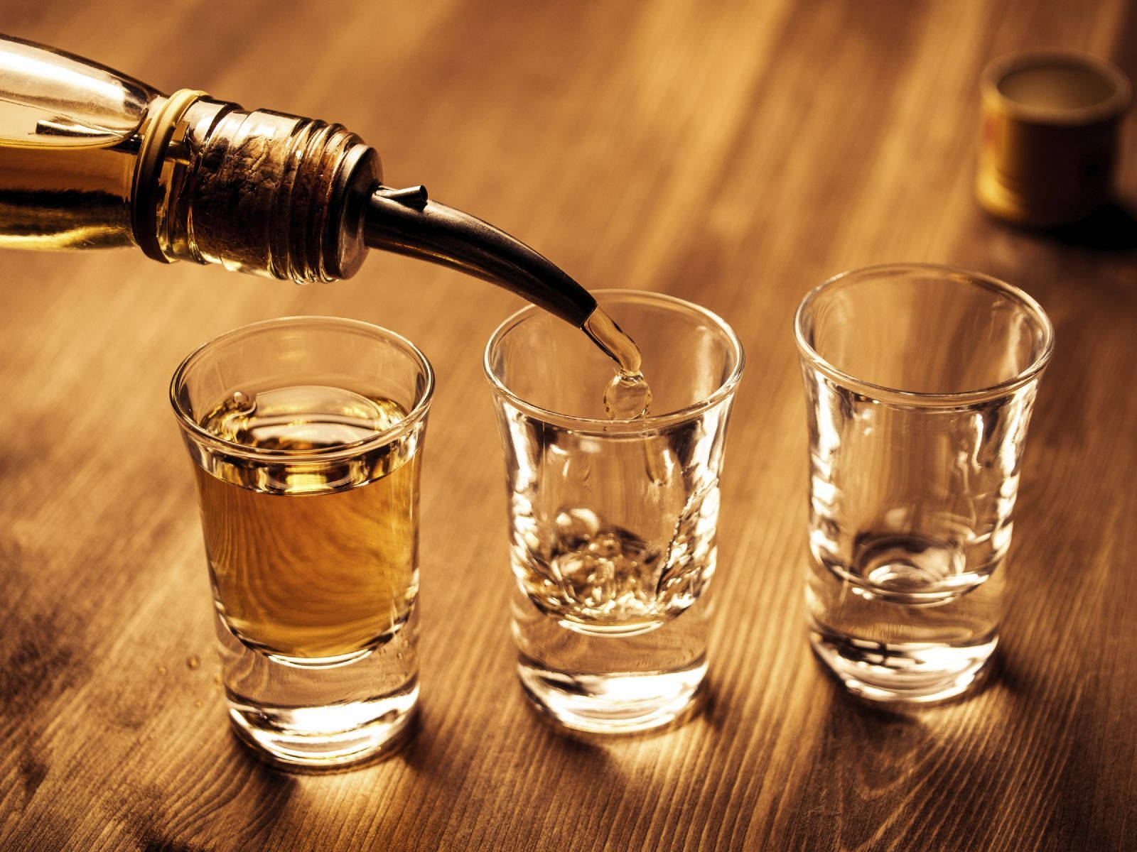 金色烈酒被倒入木桌上的小酒杯中。