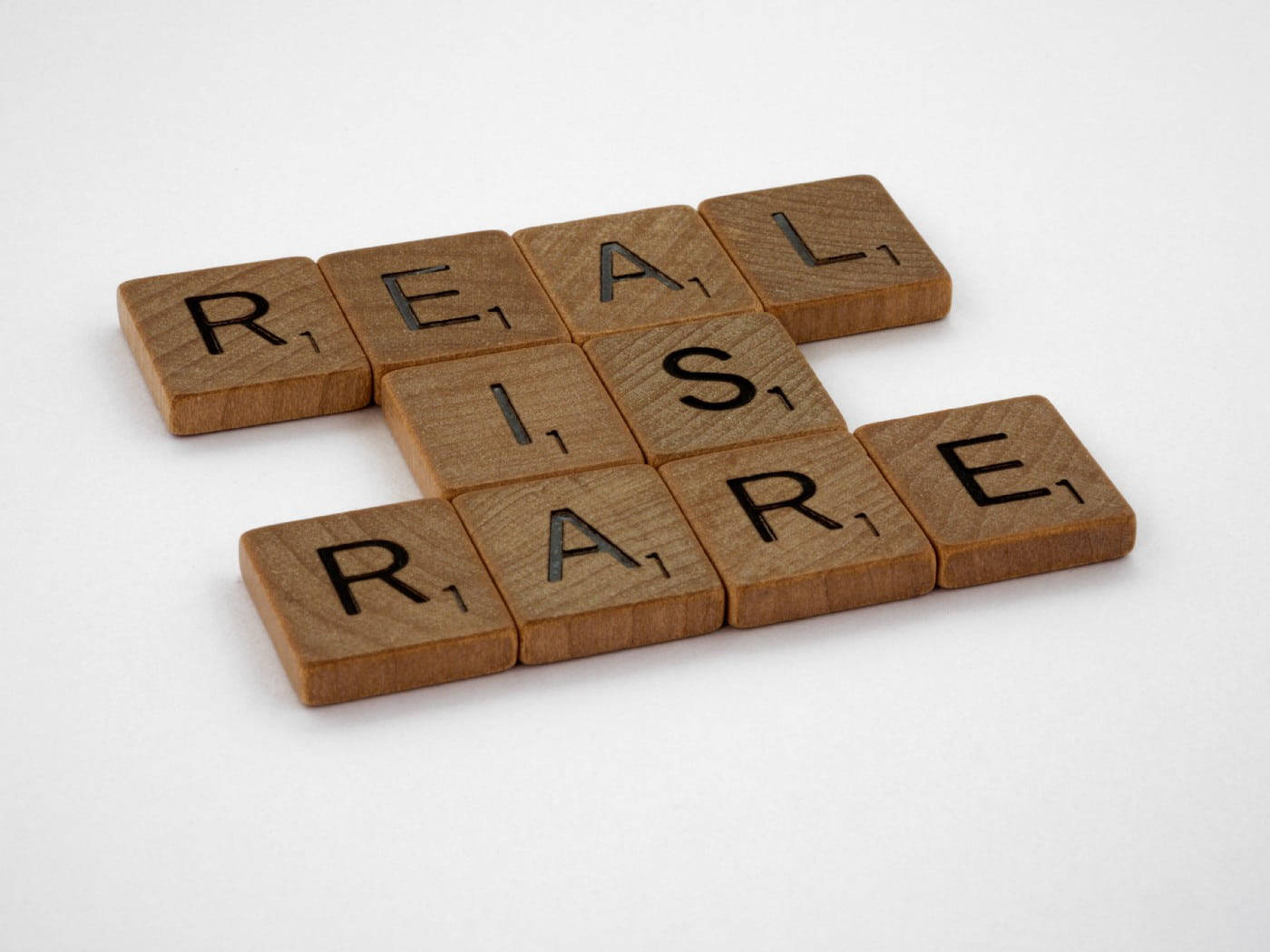 語錄 桌布 壁紙 — 木製 Scrabble 字母磚拼出 REAL RARE，以填字遊戲圖案排列在純白色背景上。