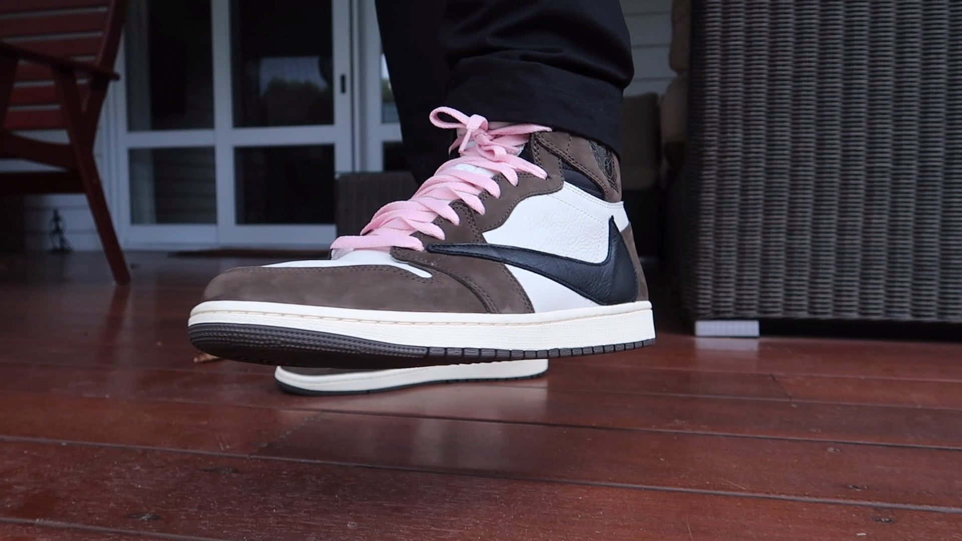 Travis Scott Jordan 1 桌布 壁紙 — 木製甲板上嘅棕色、白色同黑色Nike波鞋，配粉紅色鞋帶嘅特寫。