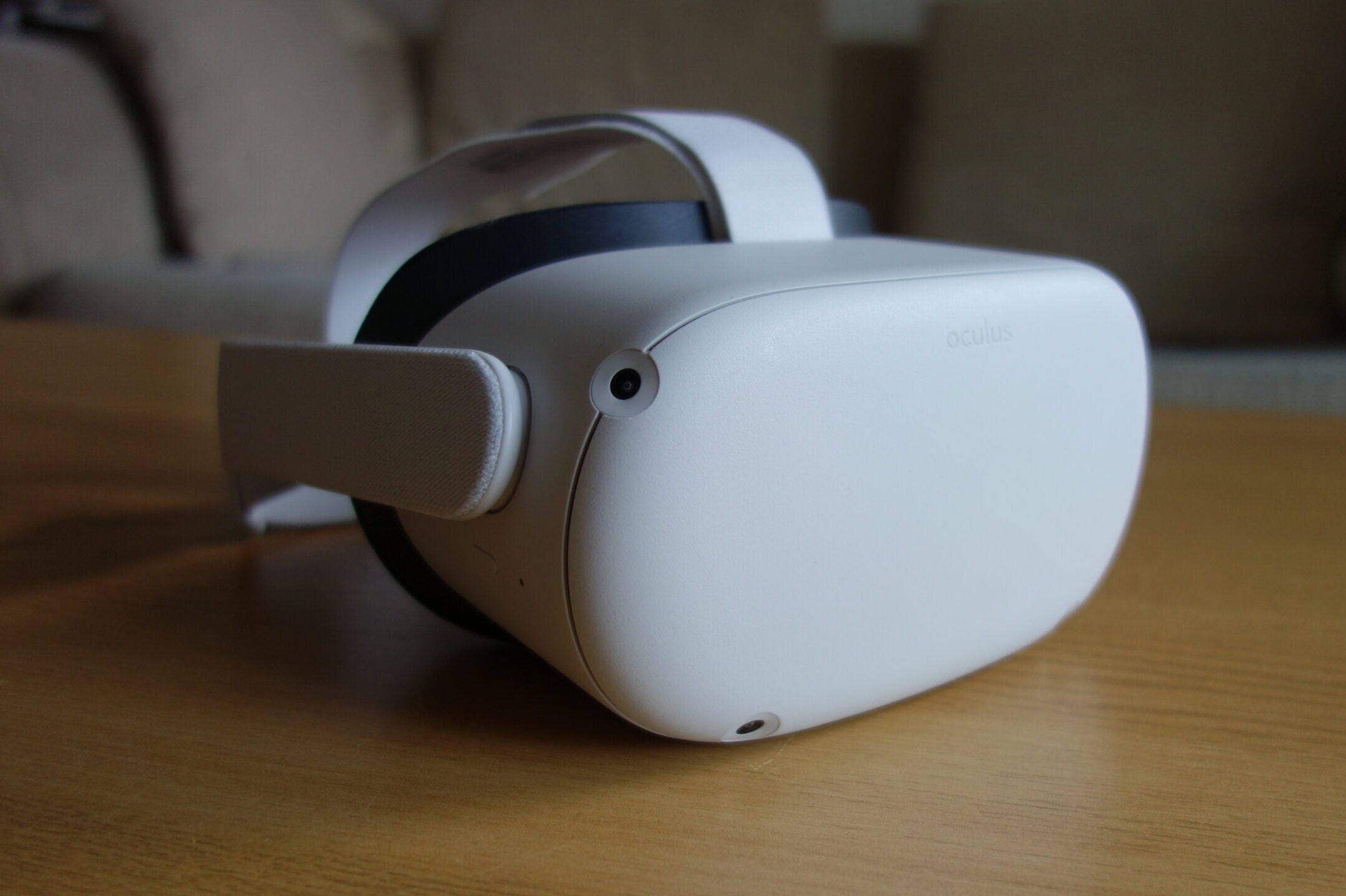 木質表面 Oculus Quest 2 壁紙 — 一個時尚的白色Oculus VR頭戴式裝置放在木桌上，伴隨著柔和自然光線。