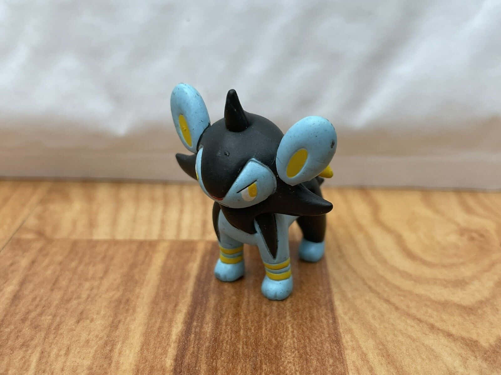 一個黑色和藍色 Umbreon 寵物小精靈玩具公仔站在木地板上。 — 任天堂 GIF 壁紙