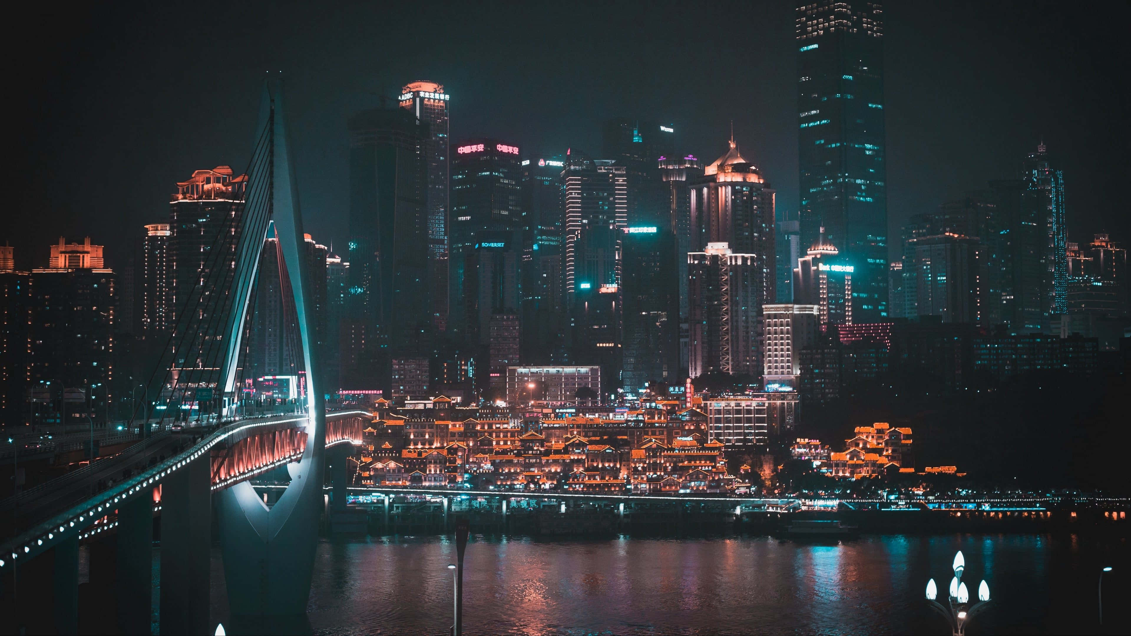 未來城市夜景 壁紙 — 現代城市景觀的壯麗夜景，一座發光的橋樑橫跨河流，反射著高聳摩天大樓的霓虹燈光。