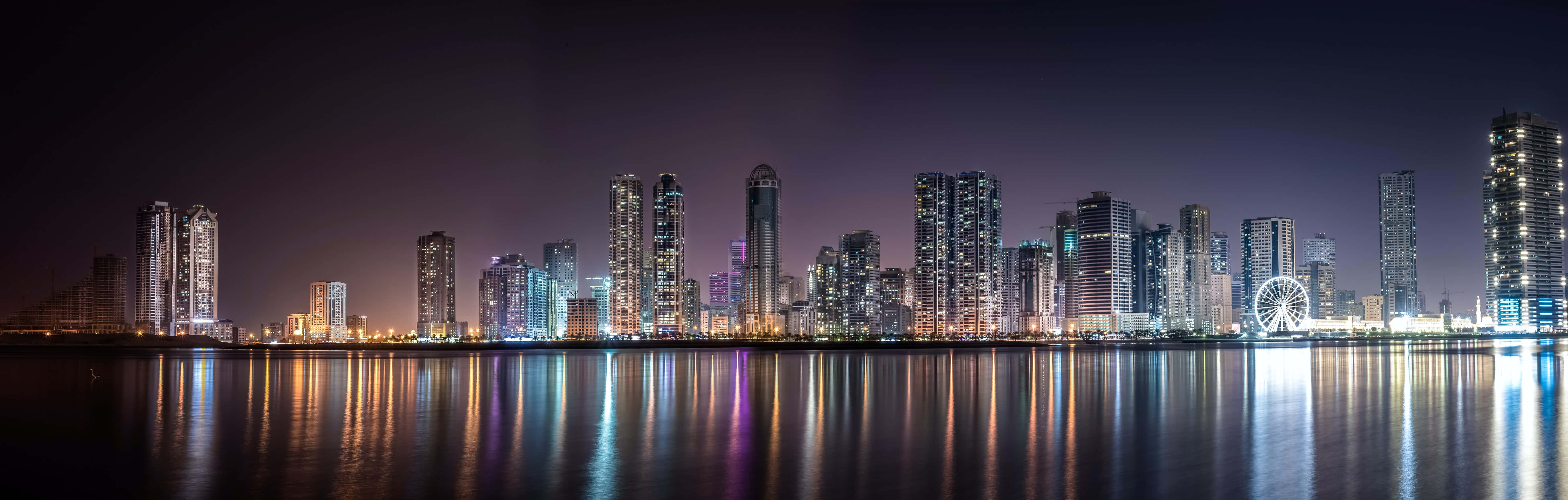 城市景觀 桌布 壁紙 — 未來城市天際線的全景夜景，閃爍的摩天大樓倒映在平靜的水面上。
