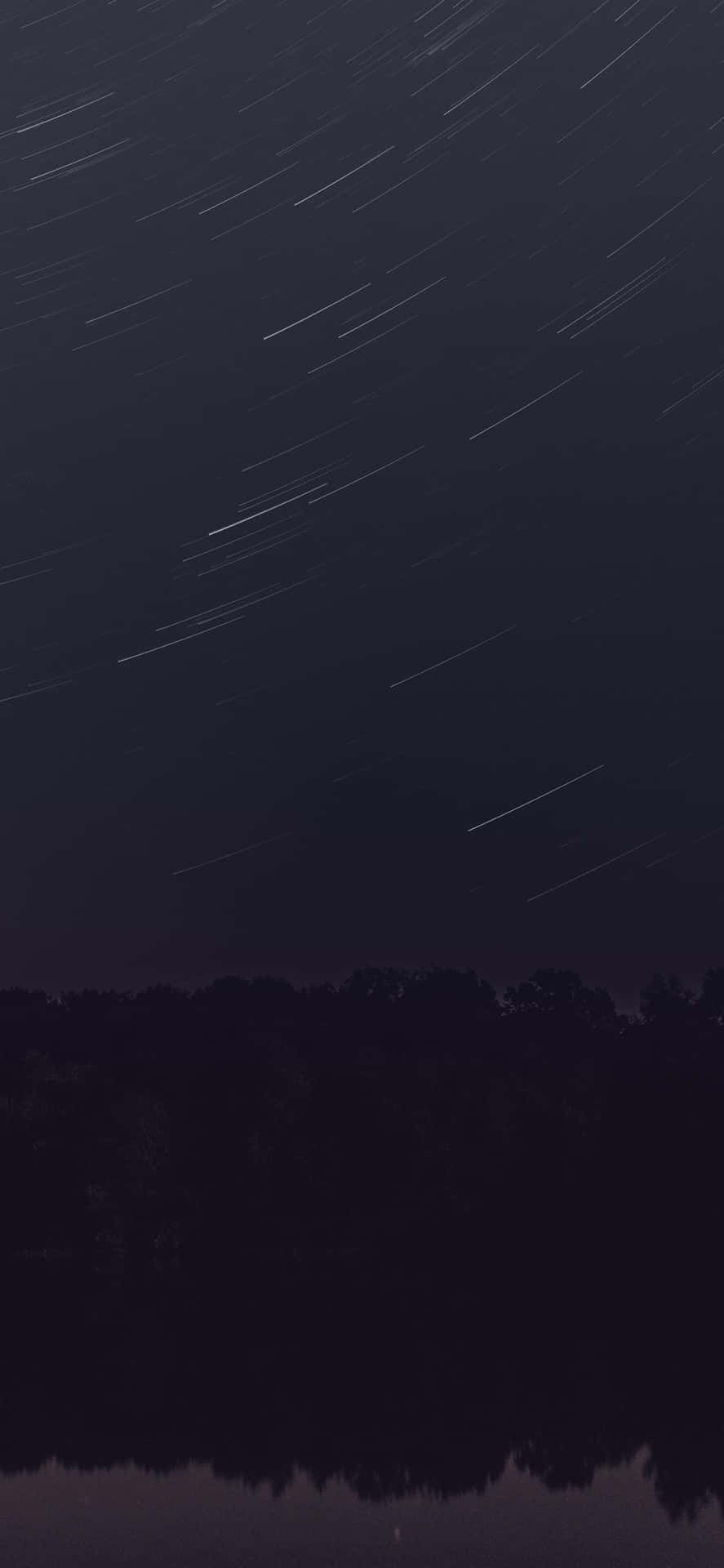 夜晚，星軌在平靜水面上倒映的黑暗森林上方。