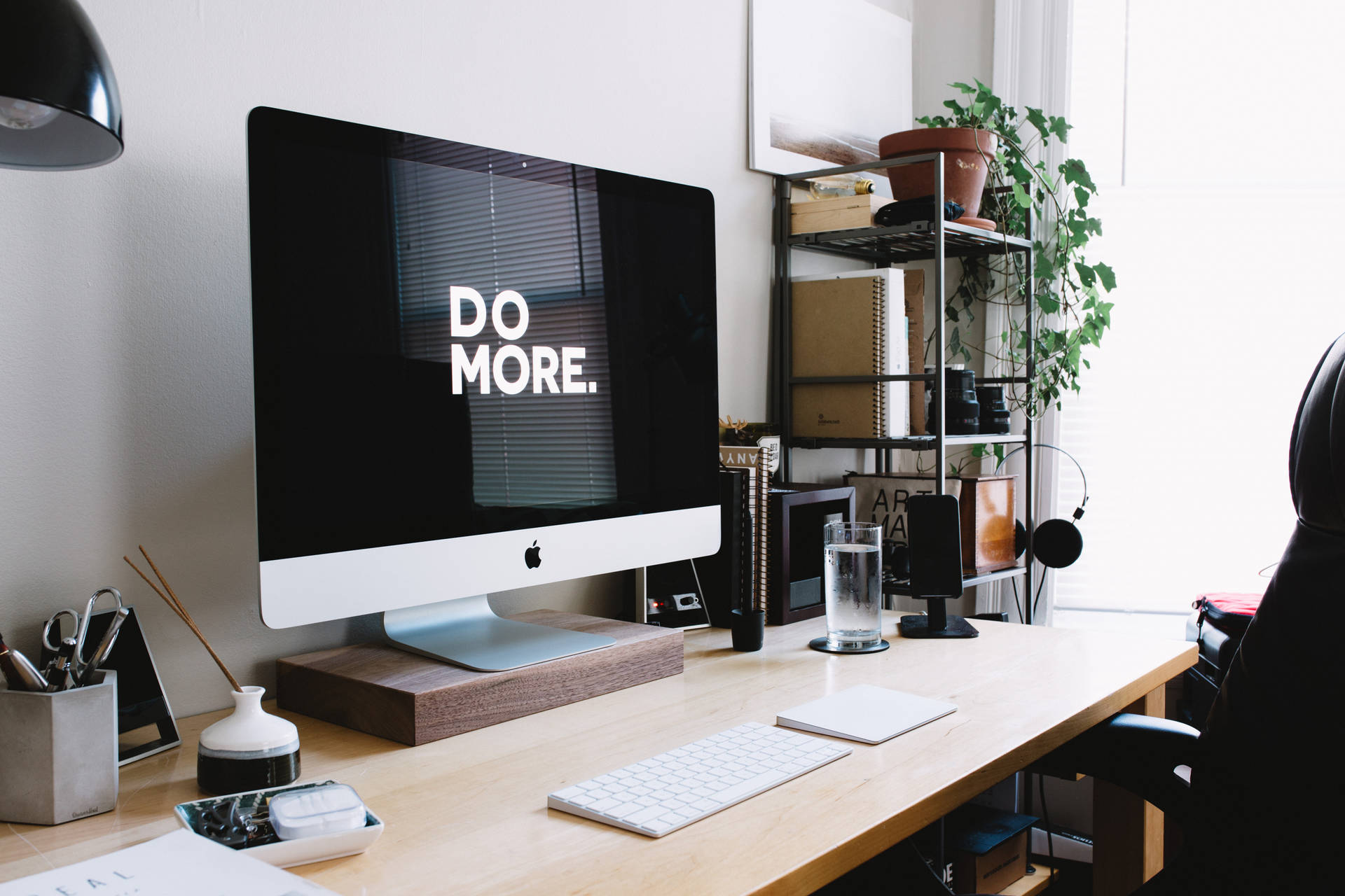 簡約家居辦公室，iMac 顯示 'DO MORE' 和盆栽植物。