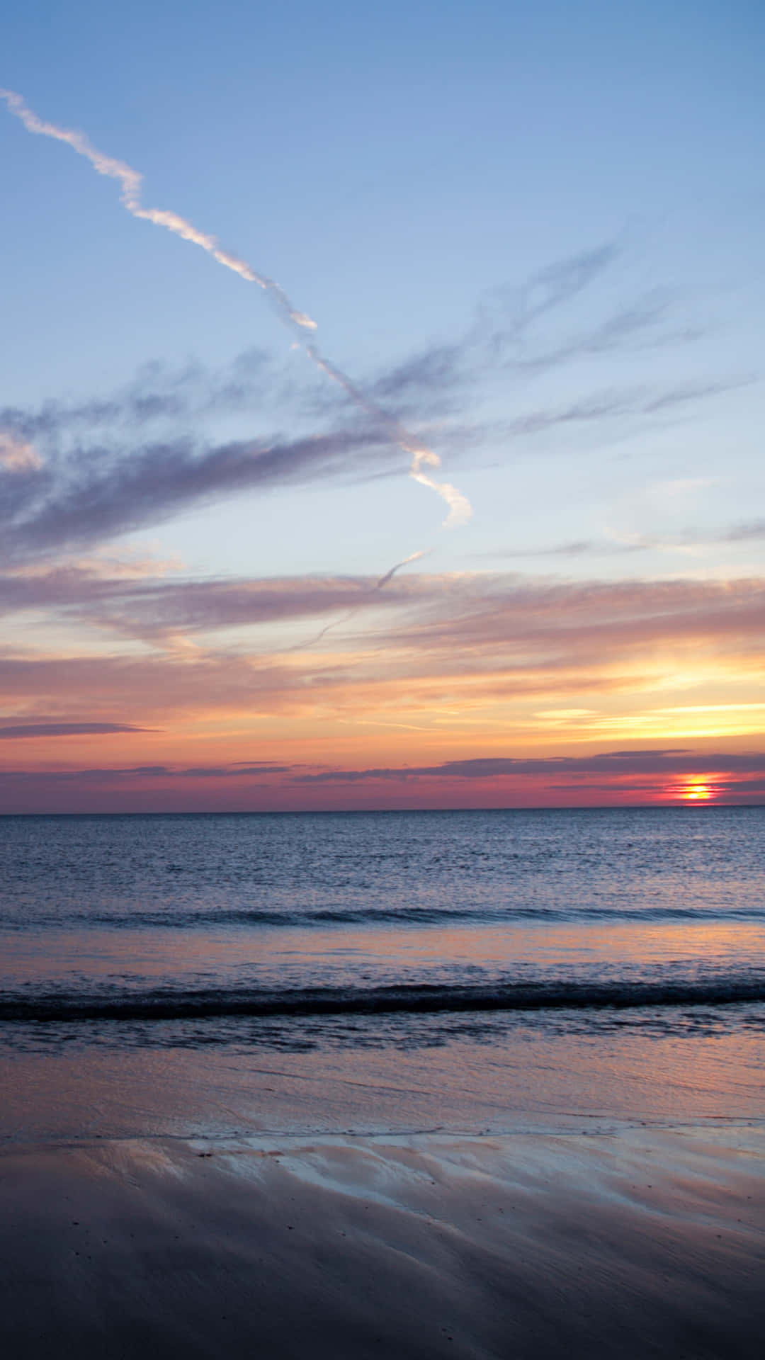 夕陽下的海洋，色彩繽紛的天空和濕沙