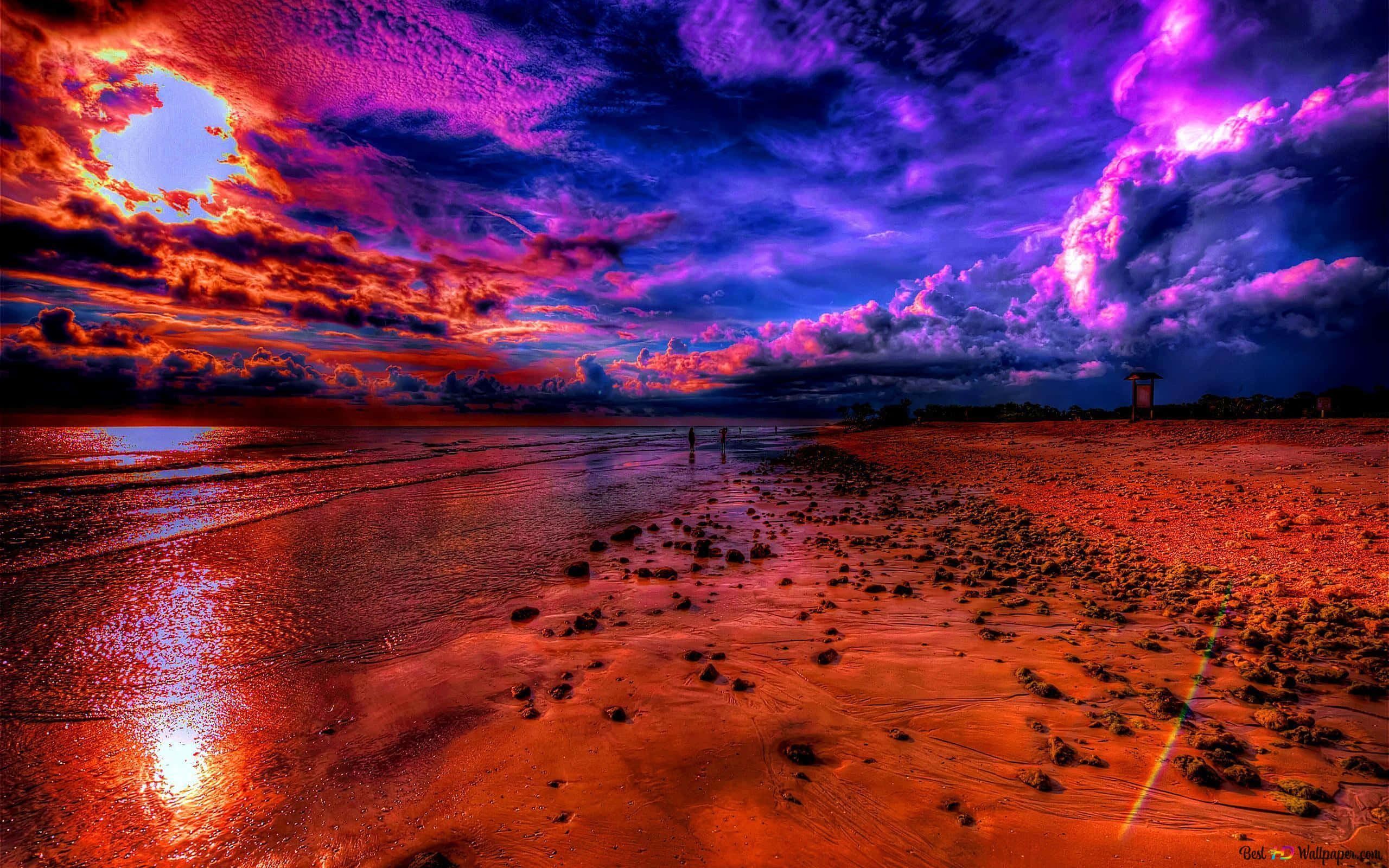 未受干擾的海灘上空寧靜的天空 壁紙 — 戲劇性的夕陽將海灘染成火紅和深紫色，海浪在暴風雨的天空下拍打著海岸。