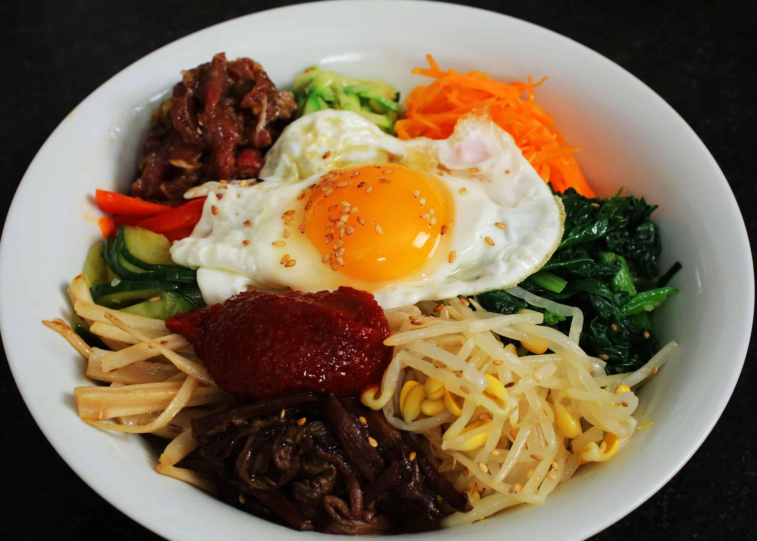 未混合的拌飯碗 壁紙 — 一碗色彩繽紛的韓國石鍋拌飯，上面放著太陽蛋和五顏六色的蔬菜。