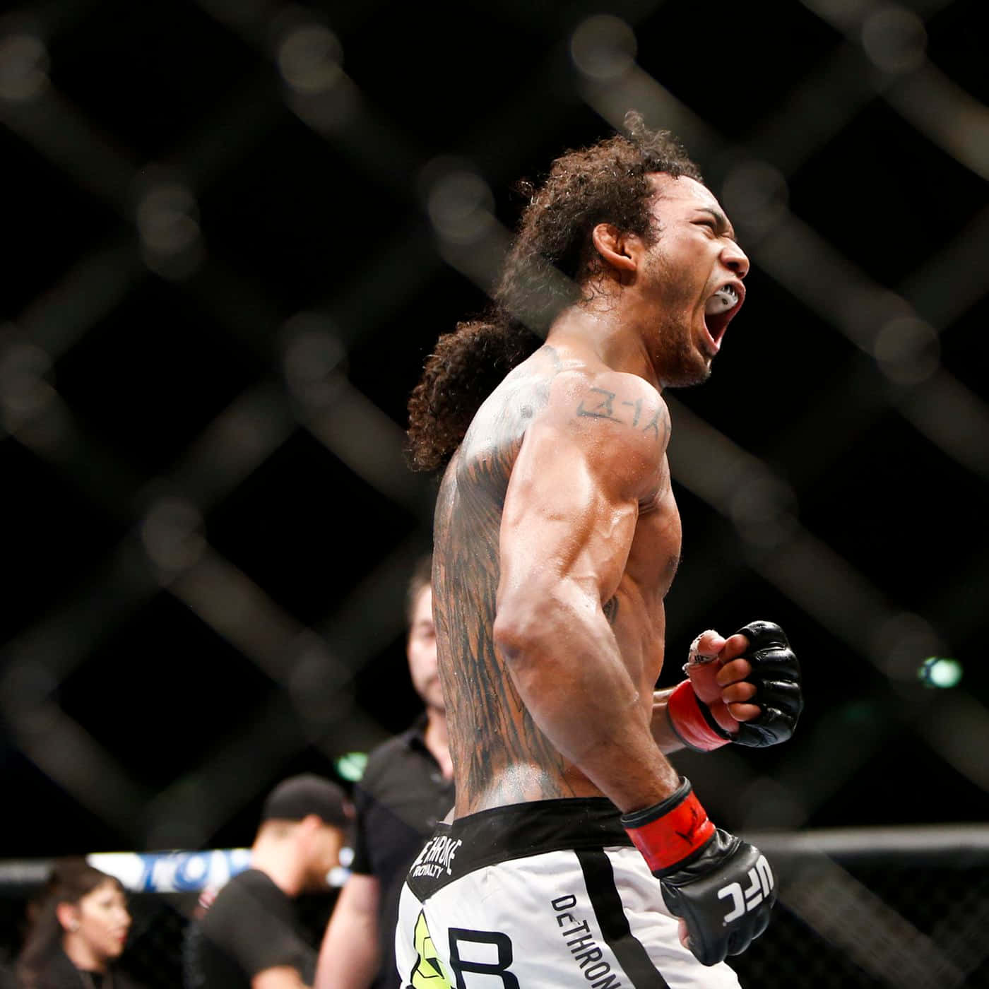 本·亨德森於UFC Fight Night 60慶祝勝利 壁紙 — 一名肌肉發達、身上有紋身的鬥士在明亮的競技場燈光下，於UFC八角籠內發出勝利的咆哮。