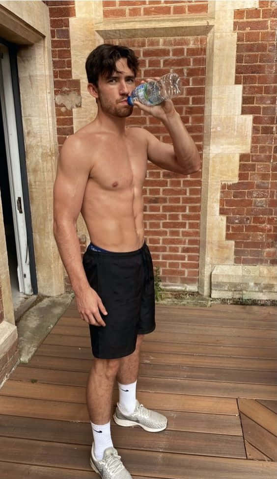 運動型男子在磚建築附近的木甲板上飲水
