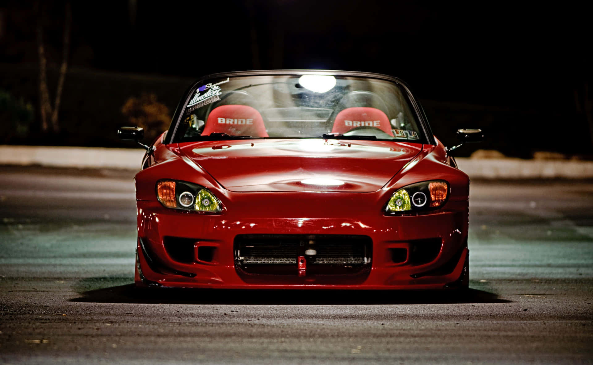 紅色跑車配備定制車頭燈，夜晚停在潮濕的瀝青路上。