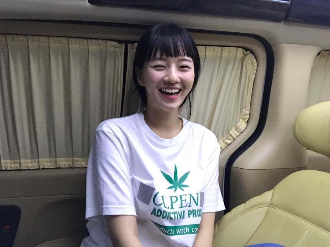 一位身穿白色T恤、面帶微笑的女性坐在米色座椅及窗簾的車內。
