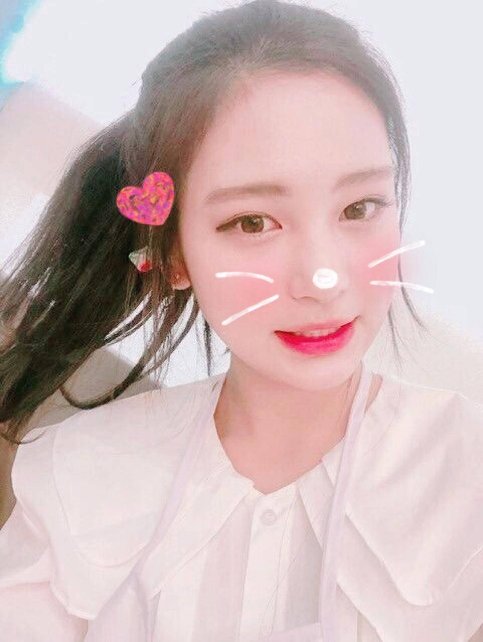 李婭可愛自拍 壁紙 — 一位深色頭髮、戴著粉紅色心形髮夾的年輕女性，帶著俏皮的貓咪濾鏡效果，溫柔地微笑。
