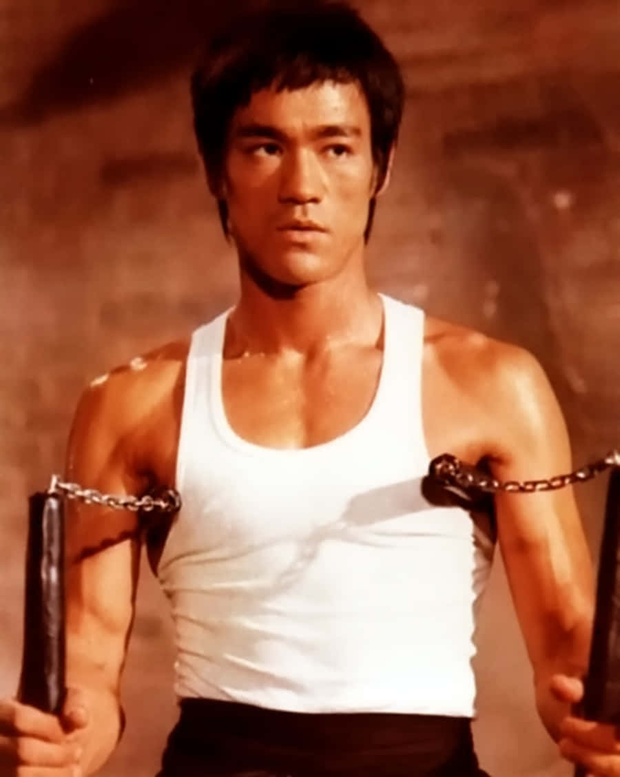 李小龍在昏暗的房間裡拿著帶鏈條的雙節棍。 — 李小龍 壁紙