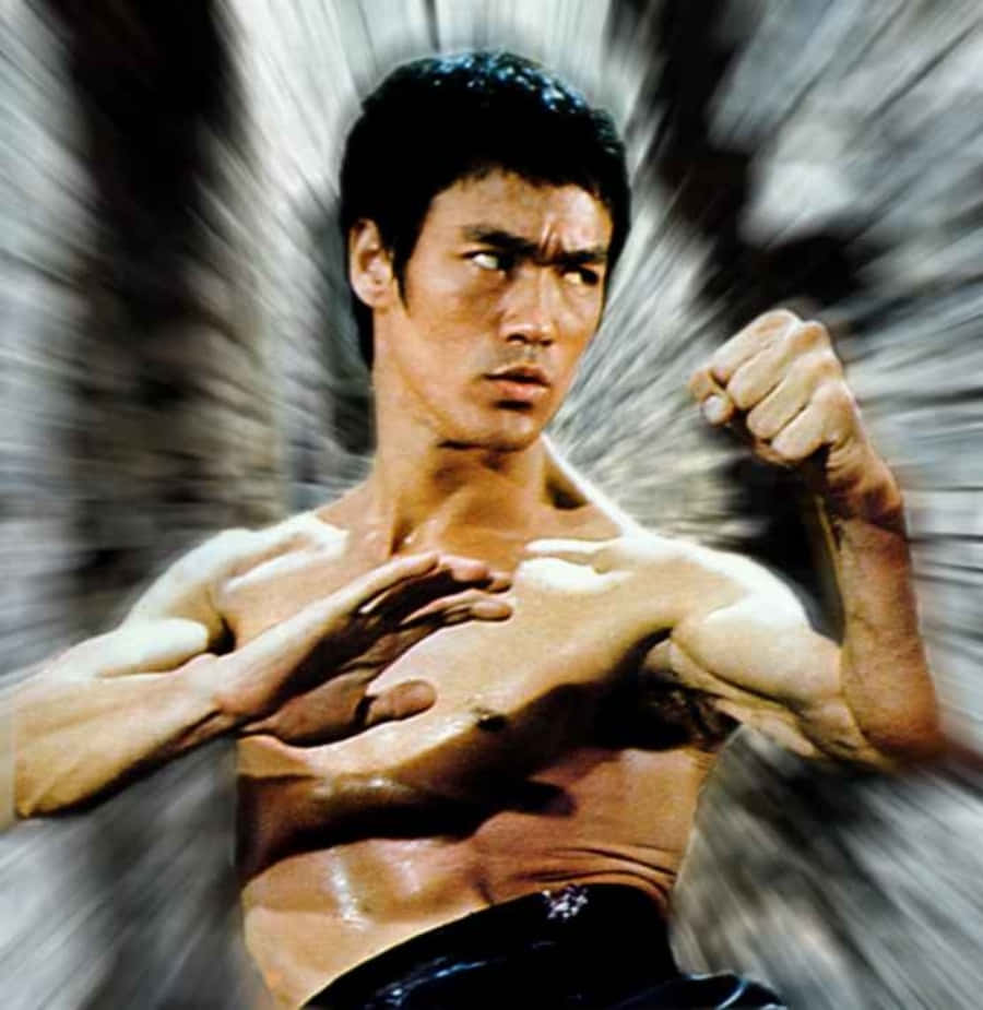 李小龍以強勁的武術姿態站立，背景帶有動態模糊效果。 — 李小龍 壁紙