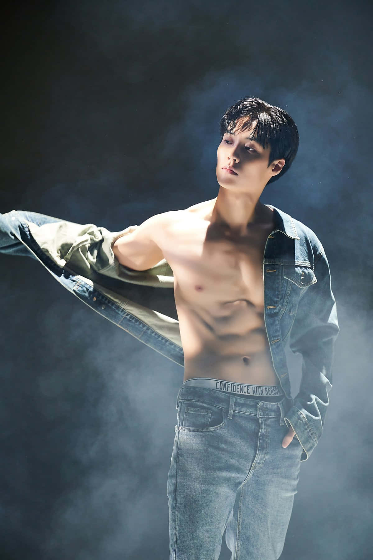 李昇炫 Denim 露腹攝影照 壁紙 — 一個赤膊上身、腹肌分明的男人，在煙霧瀰漫的黑暗背景中，以戲劇性的燈光拉開牛仔外套。