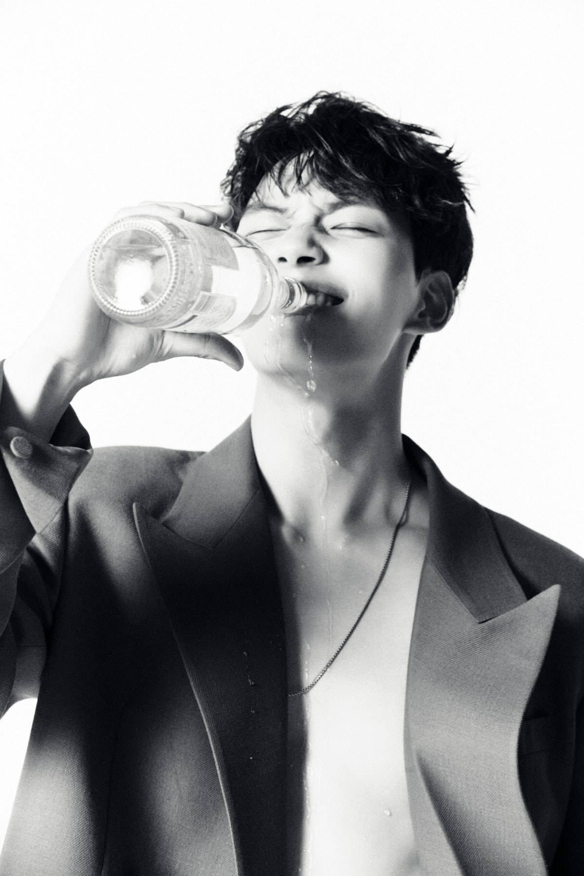 李陣郁飲水時刻 壁紙 — 一個頭髮凌亂的年輕男子在純白背景下從瓶子裡喝水，這是一張高對比度的黑白照片。