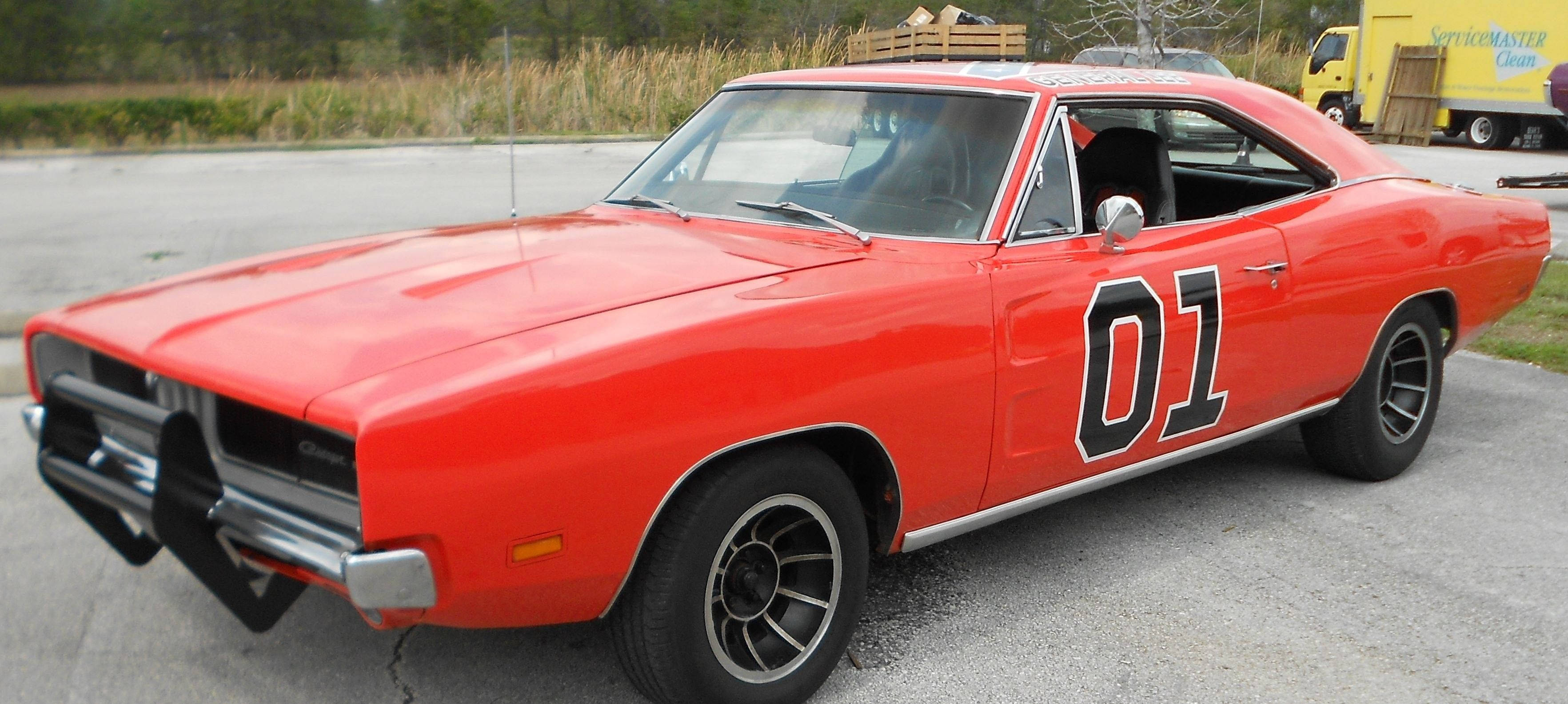 《杜克兄弟》電視劇中的經典車款「General Lee」 壁紙 — 一架鮮紅色經典肌肉車，帶有黑色賽車條紋和醒目的01貼紙，停在裂開的瀝青地上。