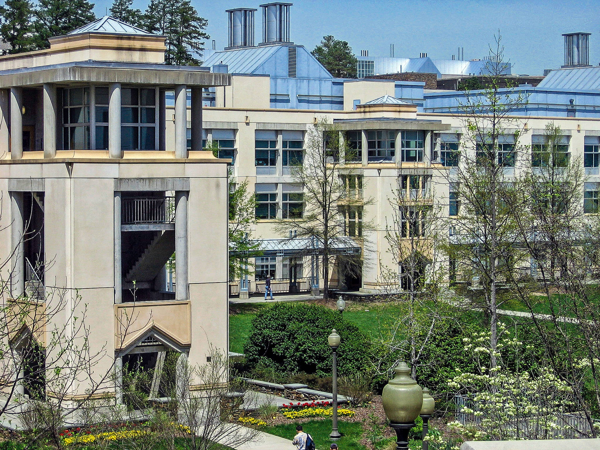 大學校園，擁有現代建築、綠色草坪和陽光明媚的日子裡盛開的樹木。