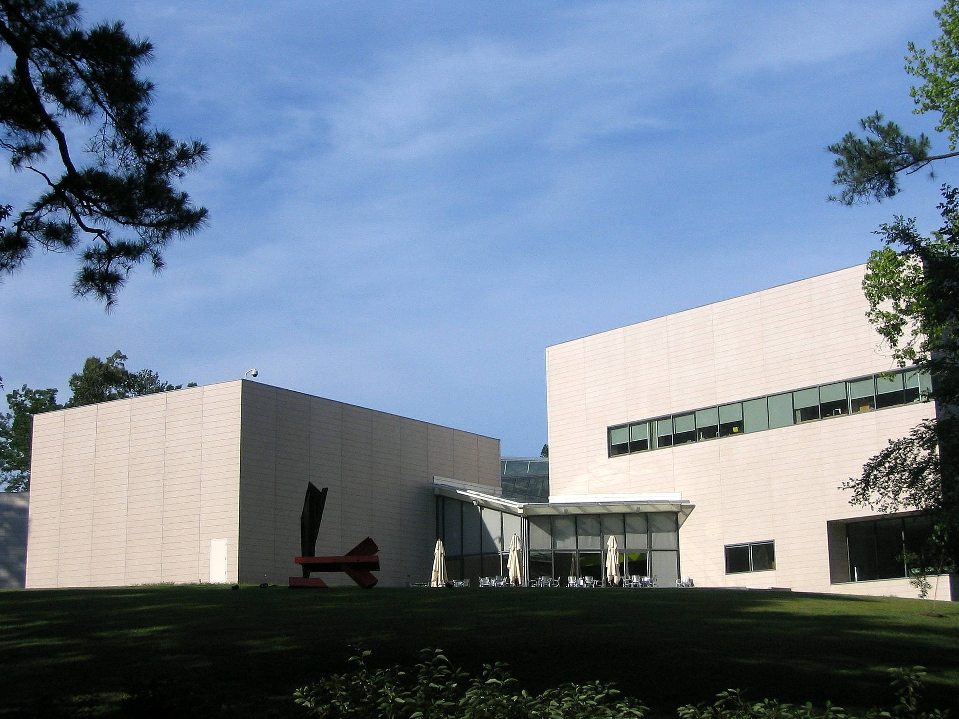 現代米色建築，配有玻璃窗和戶外庭院，在清澈藍天下。