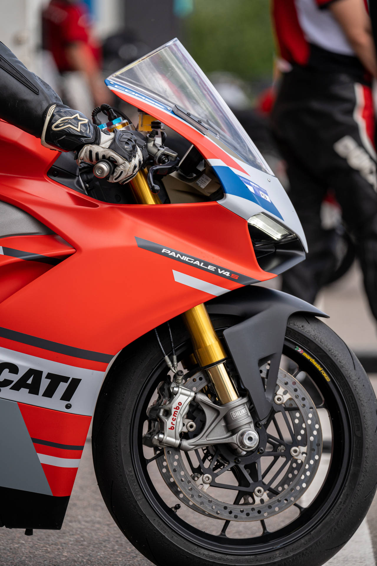 紅色Ducati Panigale V4 R電單車，騎手戴手套的手放在車把上。 — 機車 壁紙