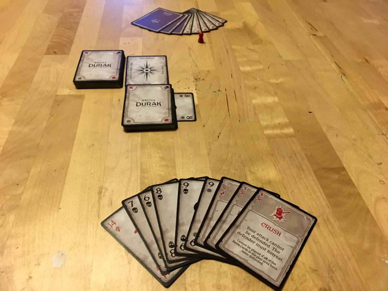 木地板上散開的 Battle Durak 牌與一個小紅色公仔。
