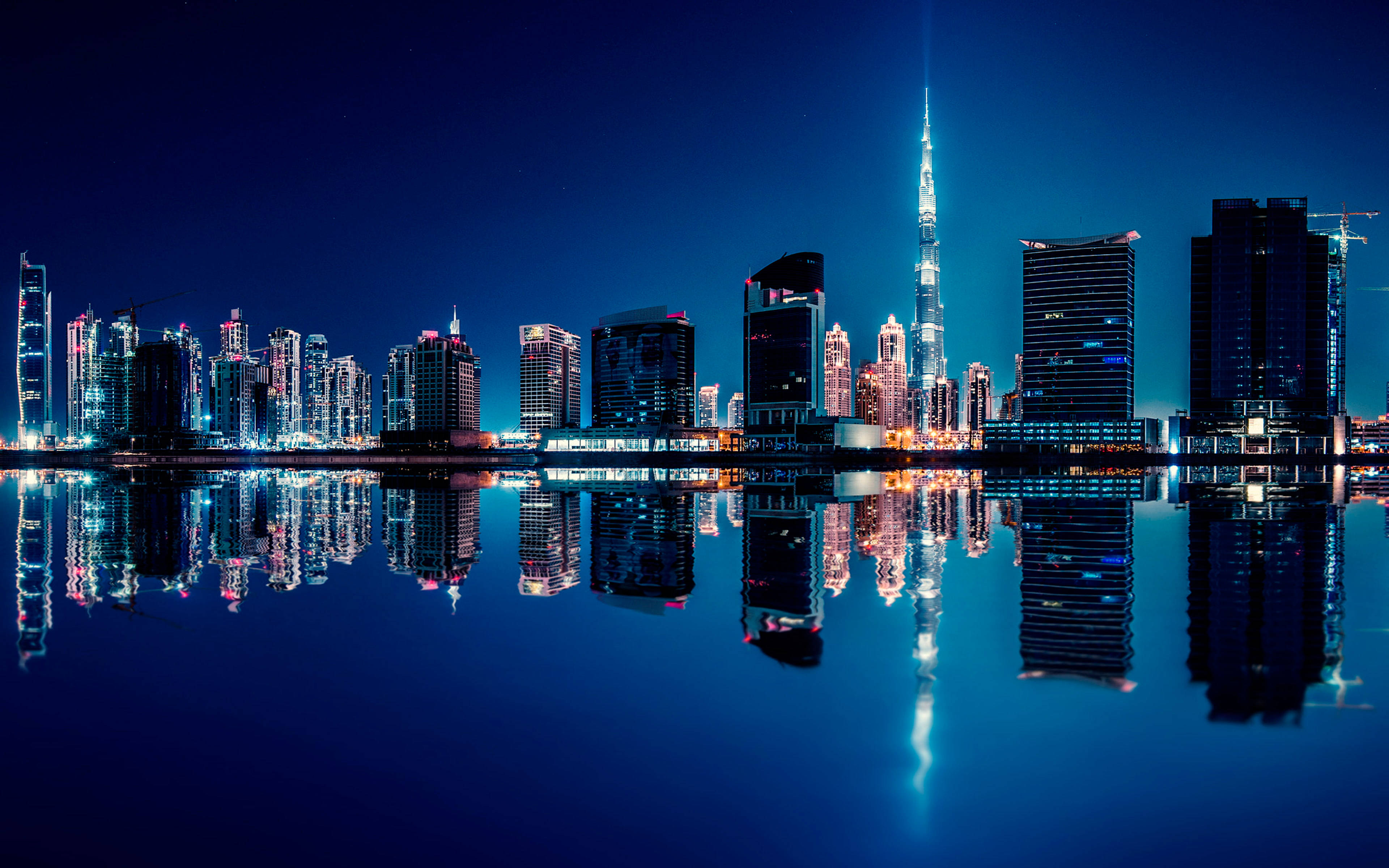 United Arab Emirates 桌布 壁紙 — 杜拜令人目眩的夜景，哈利法塔聳立在閃爍的摩天大樓之上，完美倒映在平靜的水面上。